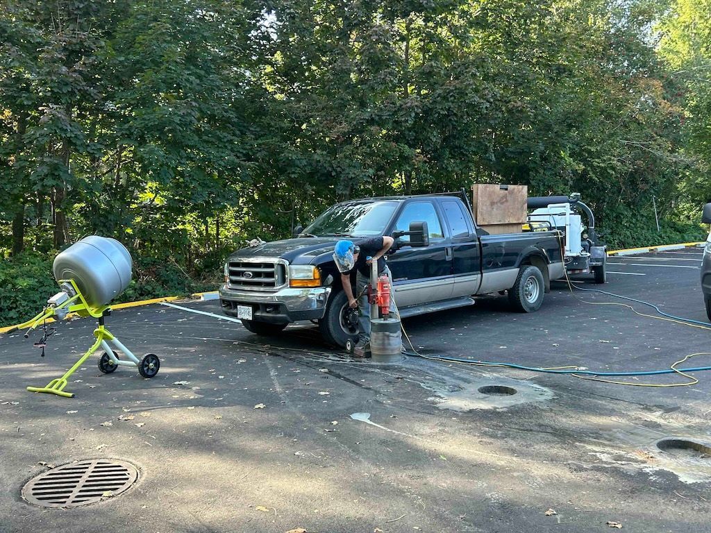 A man is standing next to a truck in a parking lot installing bollards