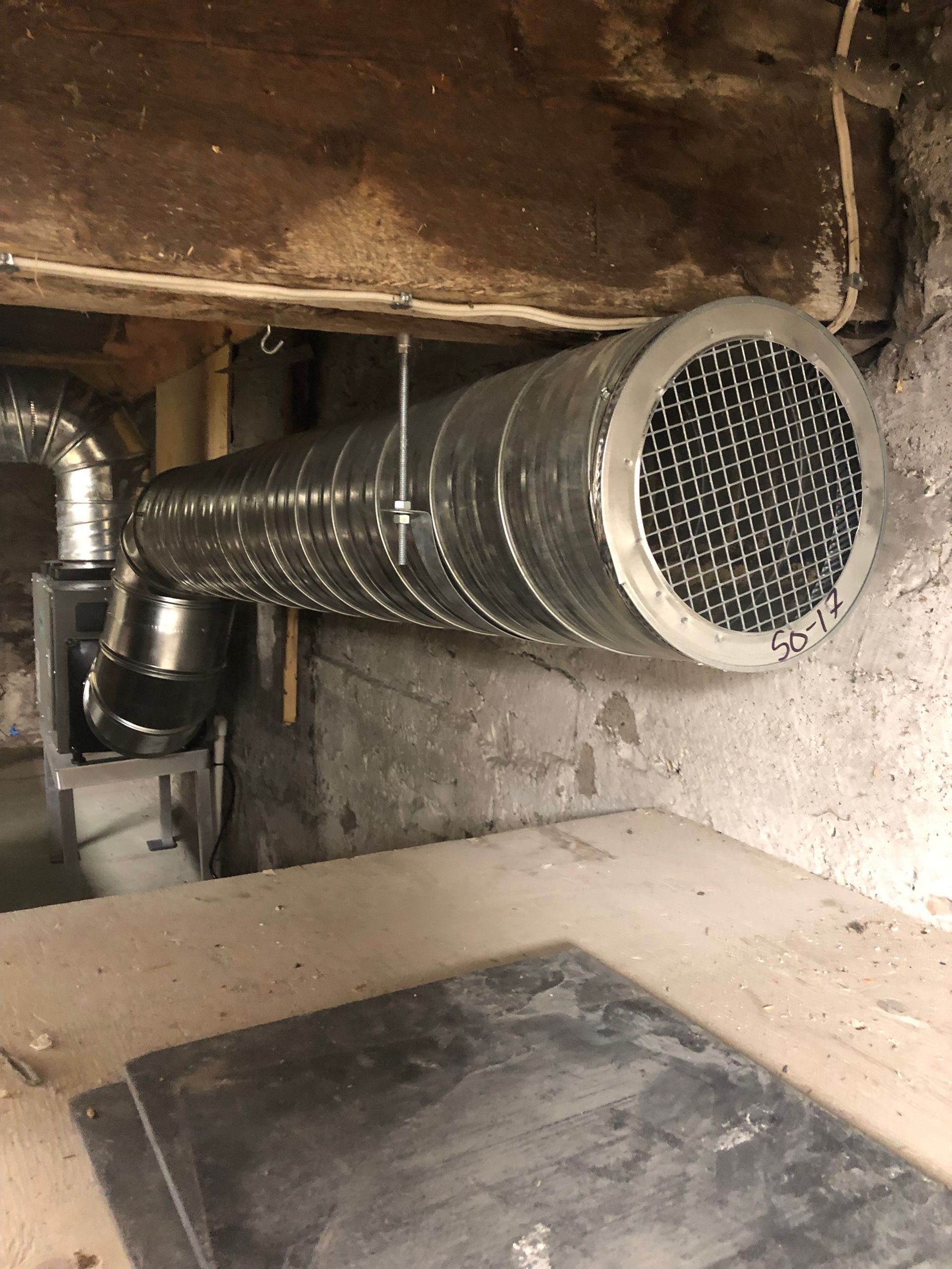 Un gros tuyau métallique est suspendu au plafond d'une pièce.