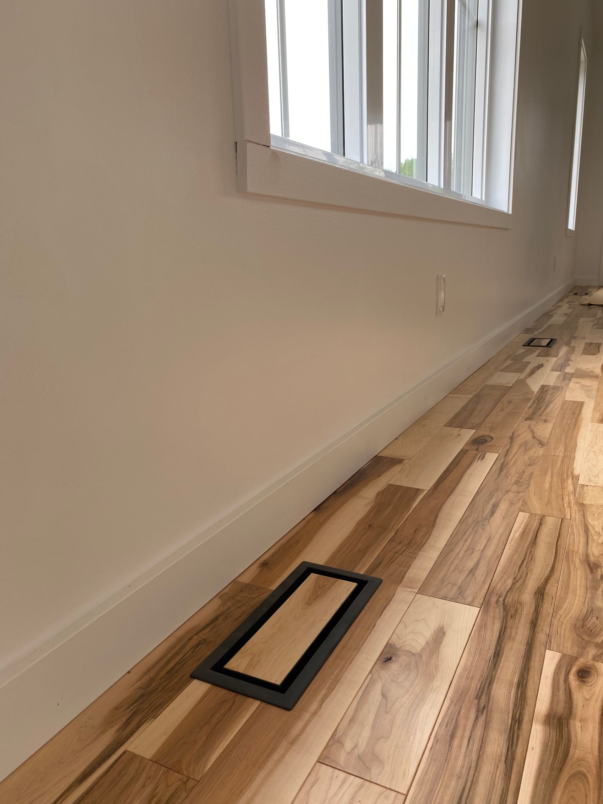 Une pièce avec un plancher en bois et une fenêtre.