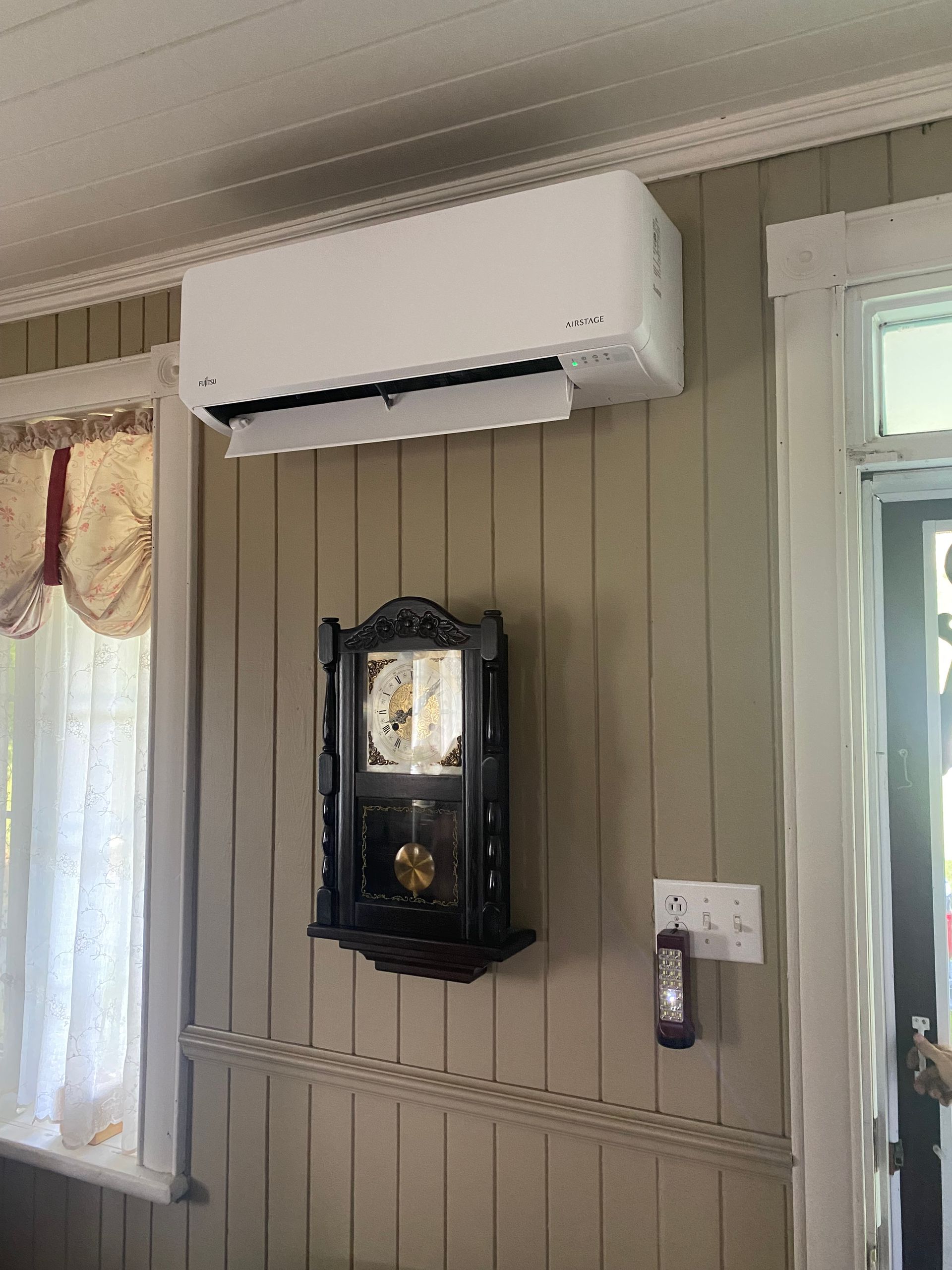 Une pièce avec une horloge et un climatiseur au mur.
