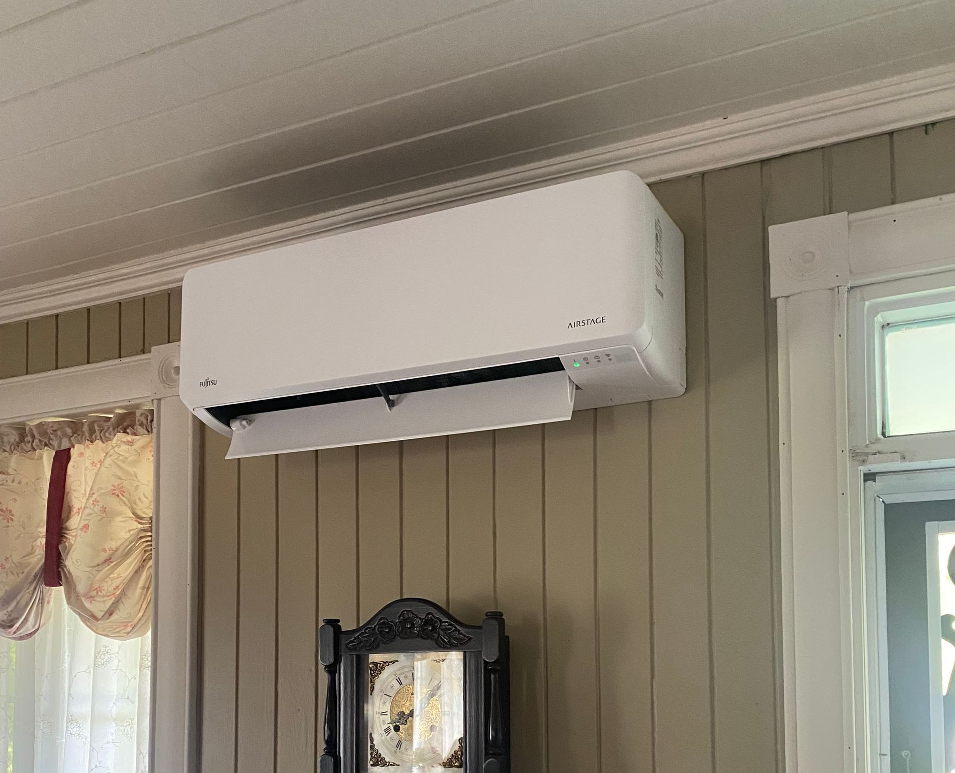 Un climatiseur blanc est suspendu au plafond d'une pièce à côté d'une horloge.