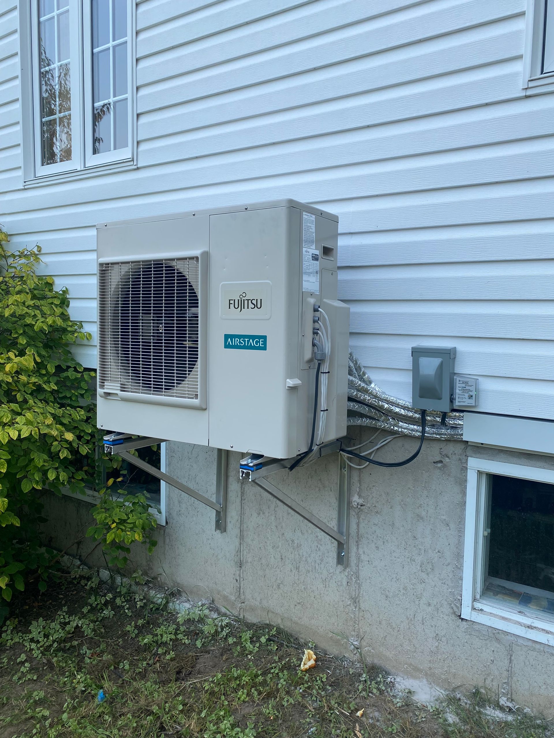 Un climatiseur blanc est monté sur le côté d'une maison.