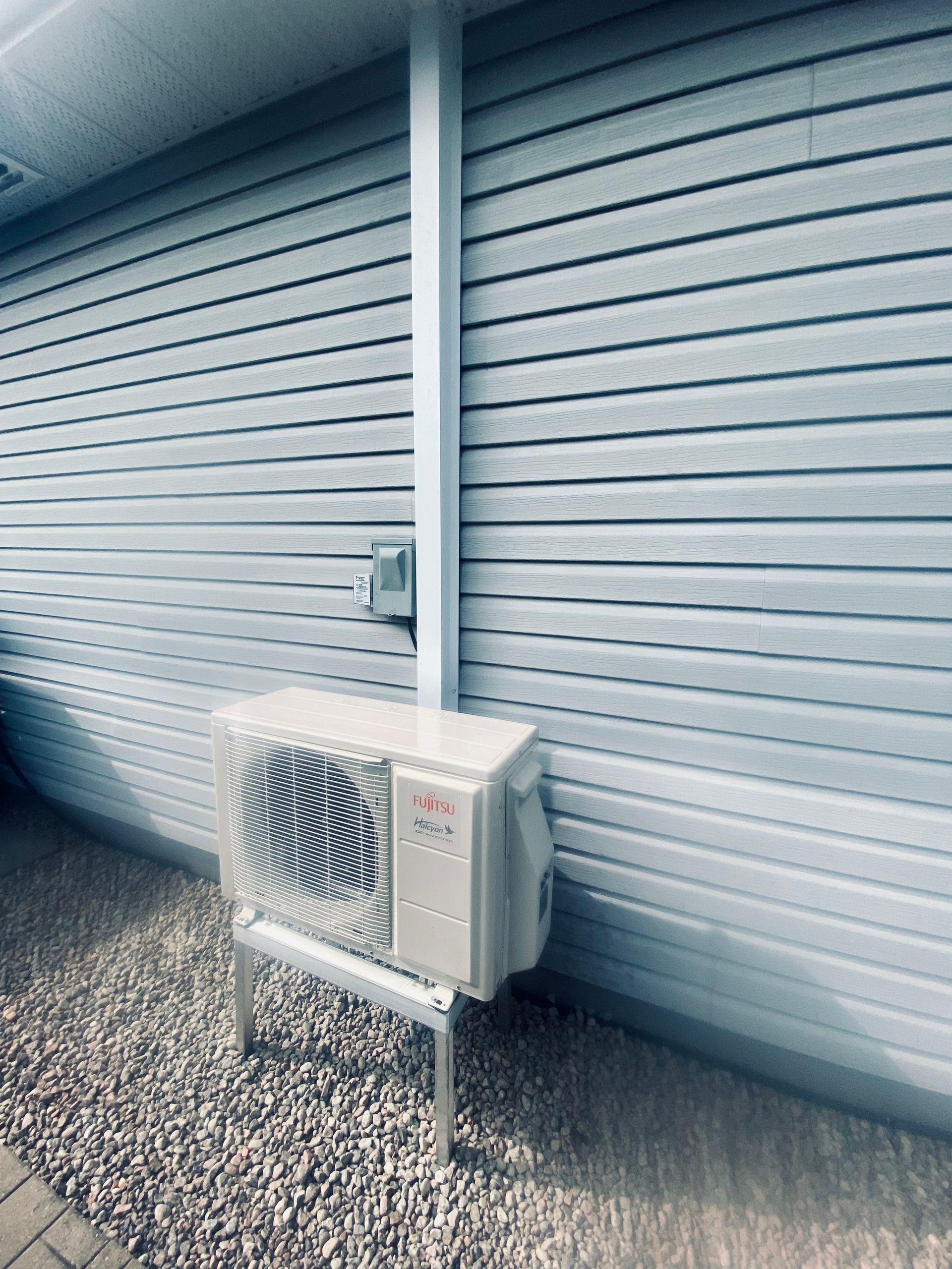 Un climatiseur blanc est posé sur le côté d'une maison.