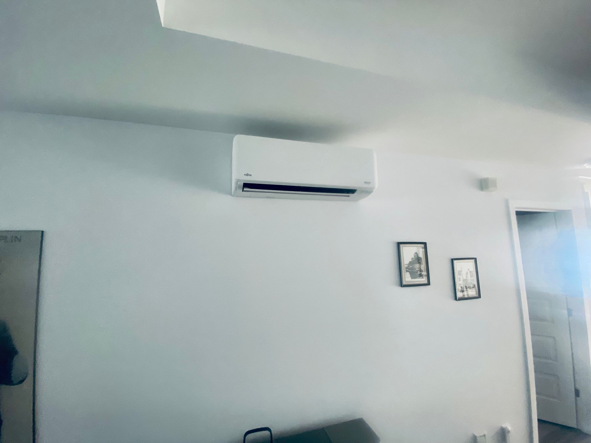 Une pièce avec un mur blanc et un climatiseur blanc suspendu au plafond.