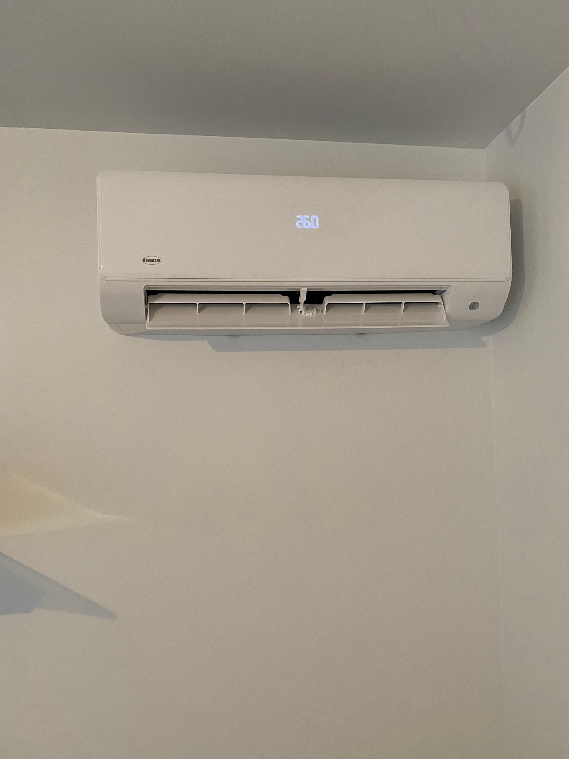 Un climatiseur blanc est accroché sur un mur blanc dans une pièce.