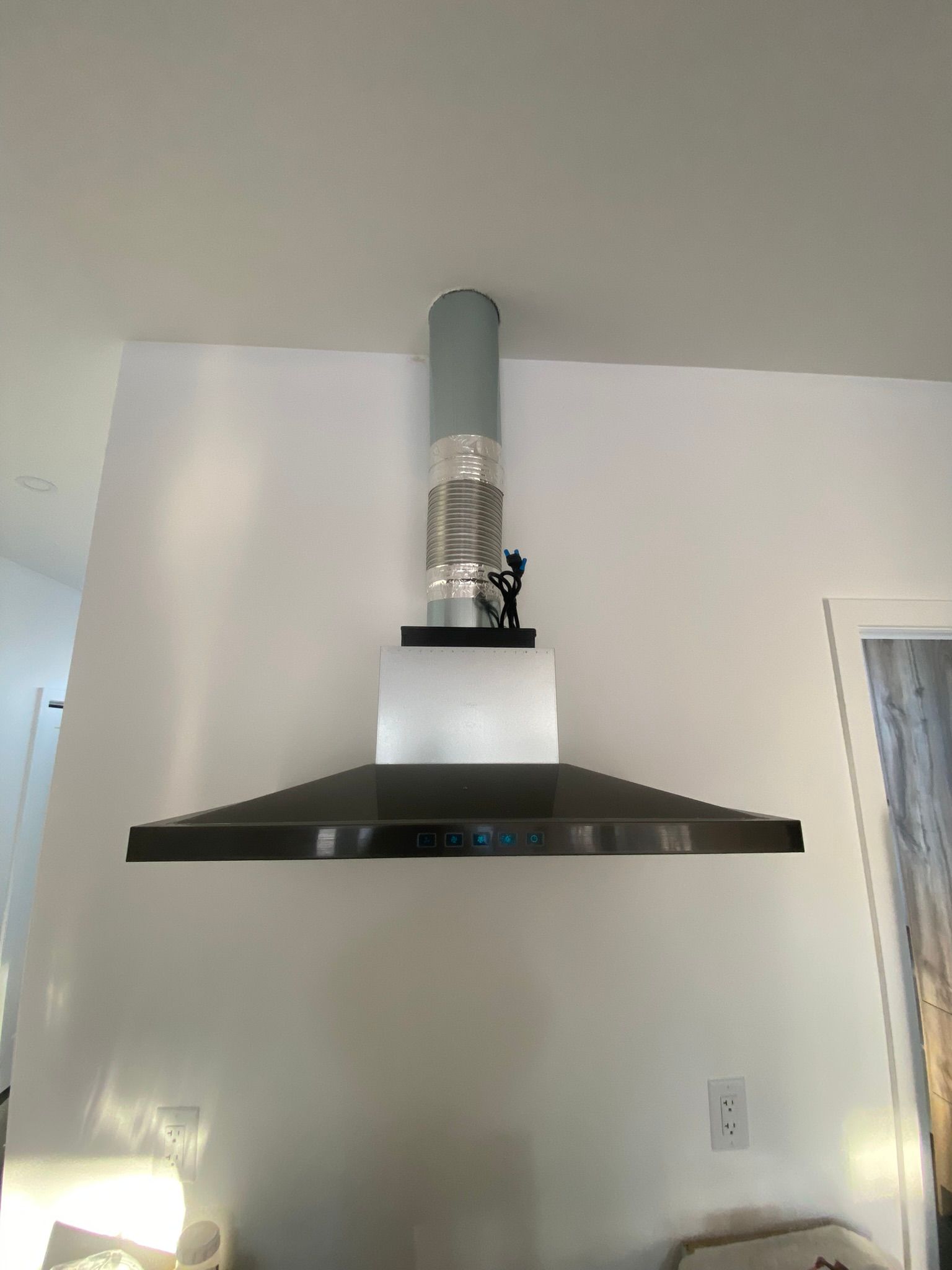 Une hotte en acier inoxydable est suspendue au plafond dans une cuisine.