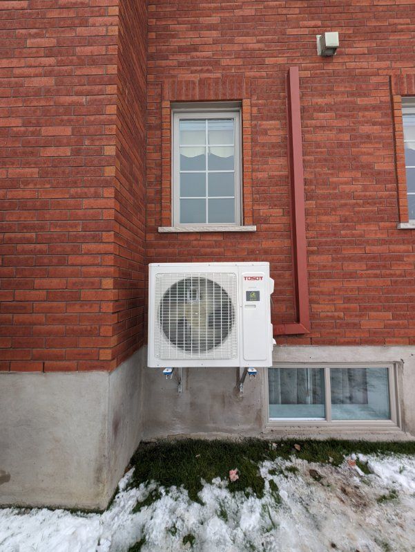 Un climatiseur blanc est monté sur le côté d'un bâtiment en briques.