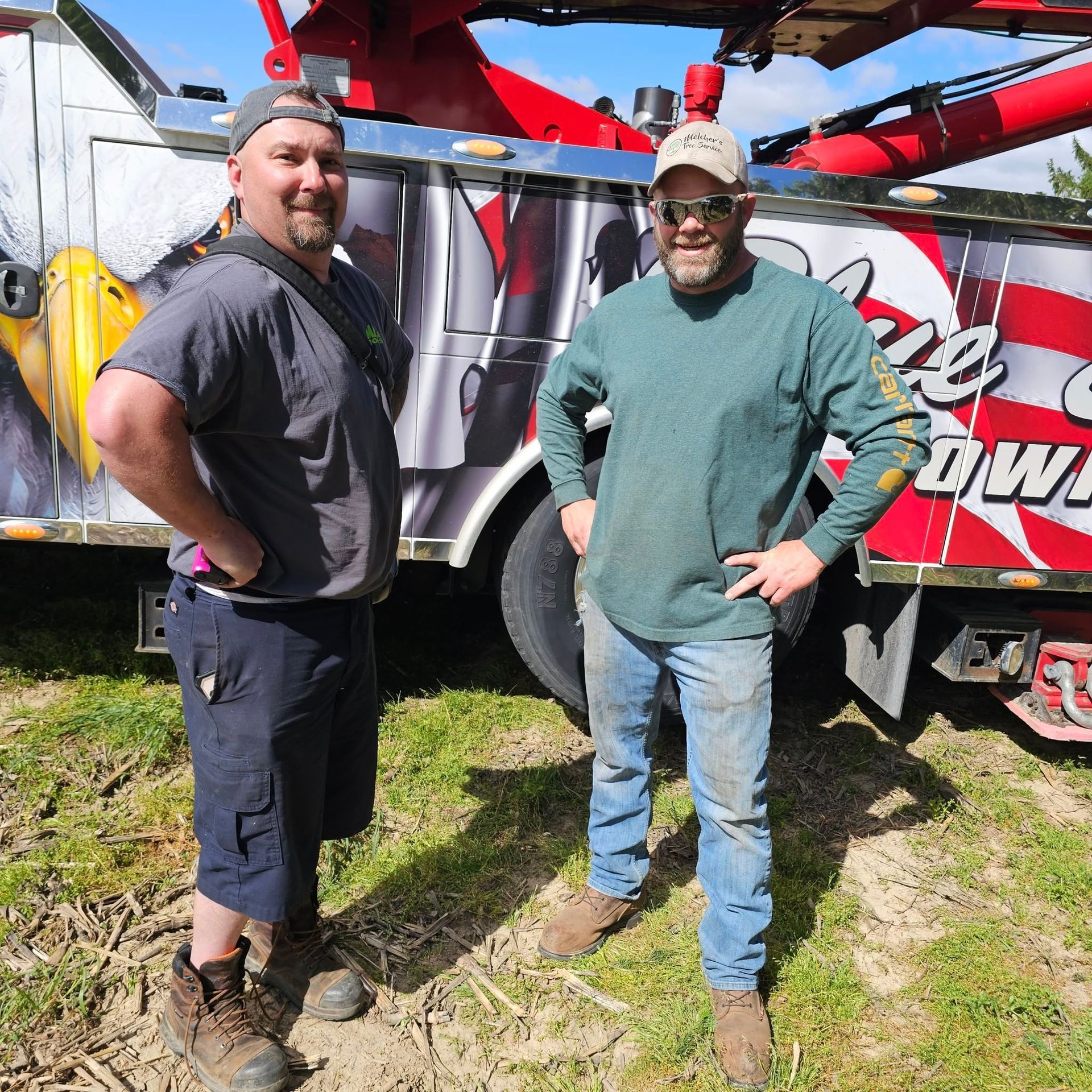 Two men standing in front of a tow truck that says owl