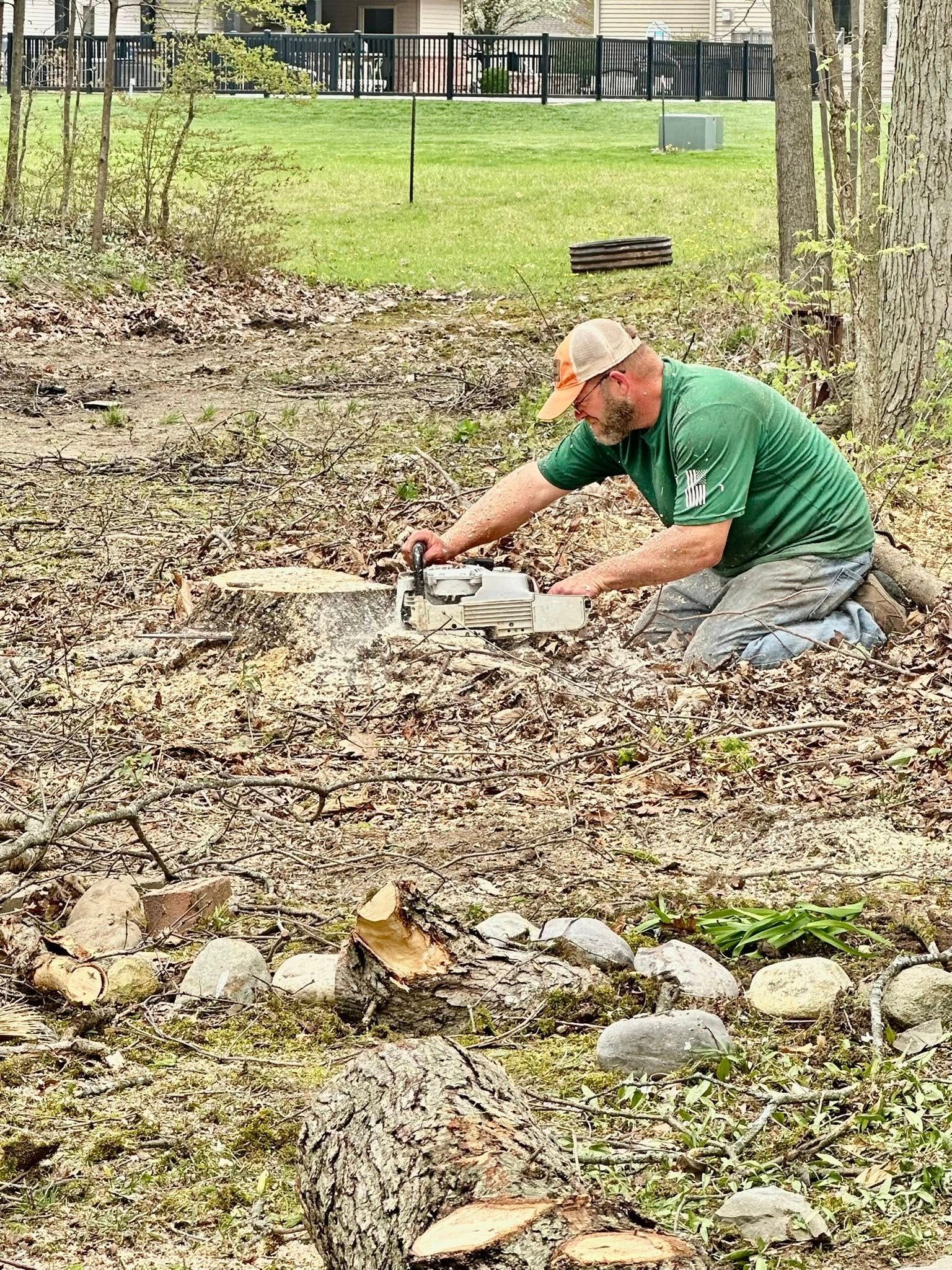 A man in a green shirt is kneeling down in the dirt.