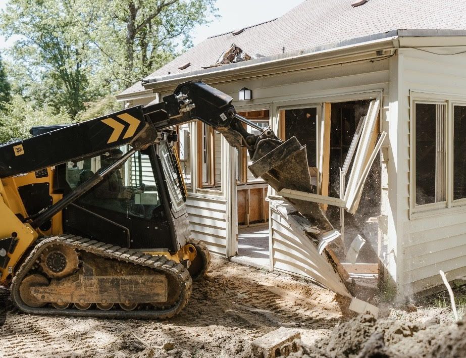 A crane is being used to remove a tree from a house.
