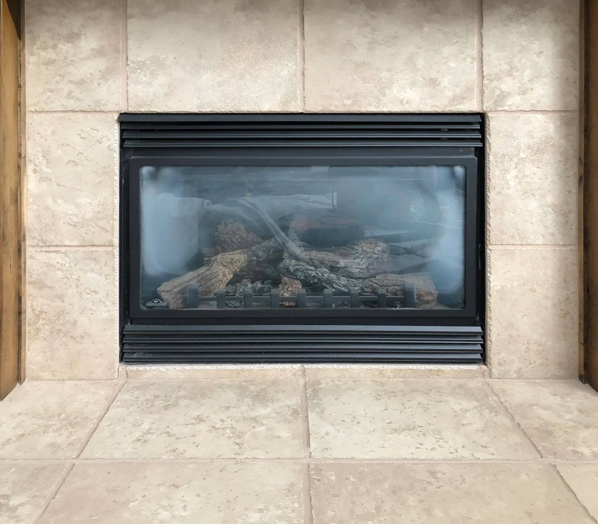 Wooden fireplace with an electric fire, a TV above, and tools on a drop cloth.