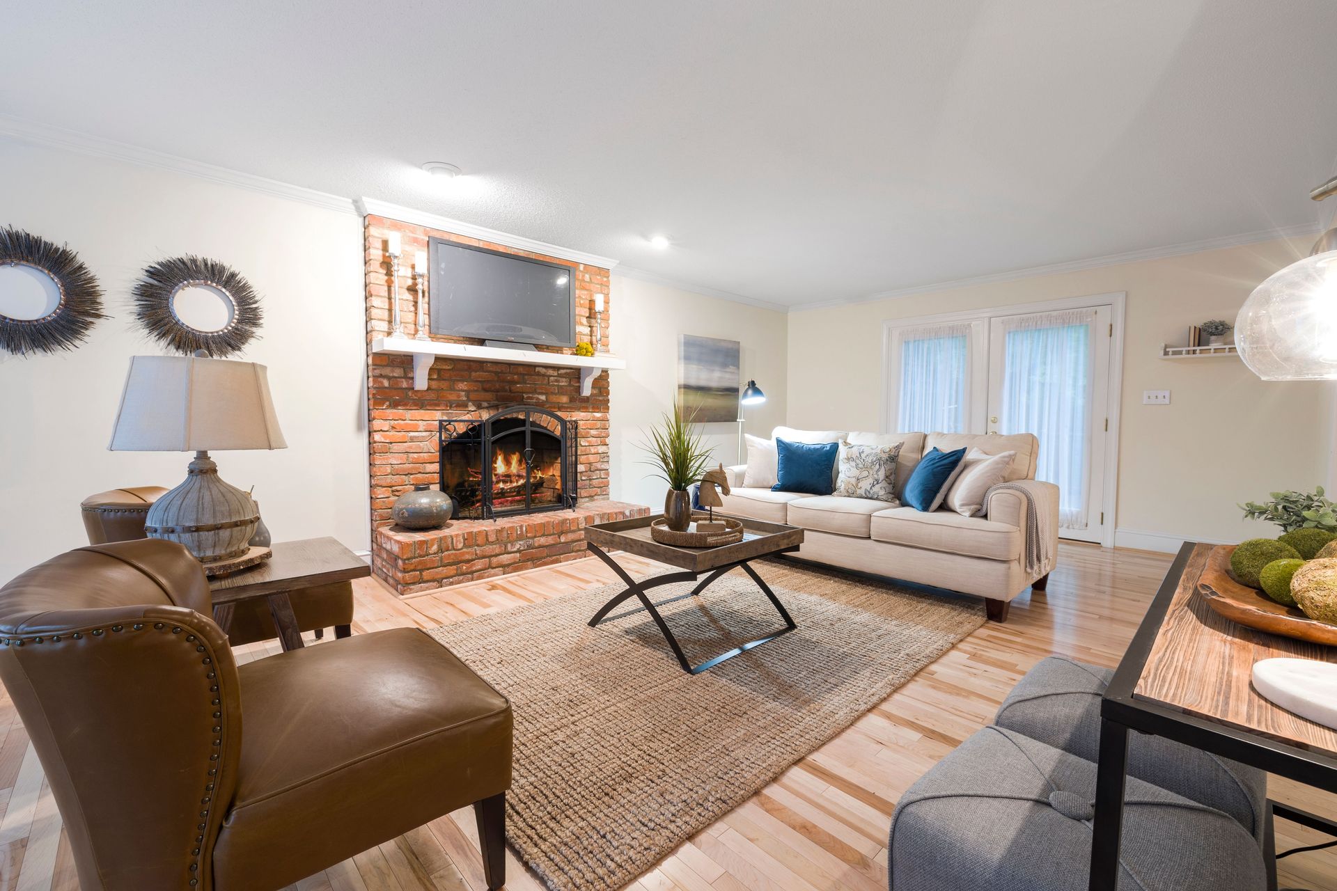 Cozy living room with fireplace, beige sofa, armchairs, coffee table, and warm lighting