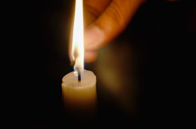 Hand lighting a memorial candle, creating a calm tribute moment in Bedford Park, IL.