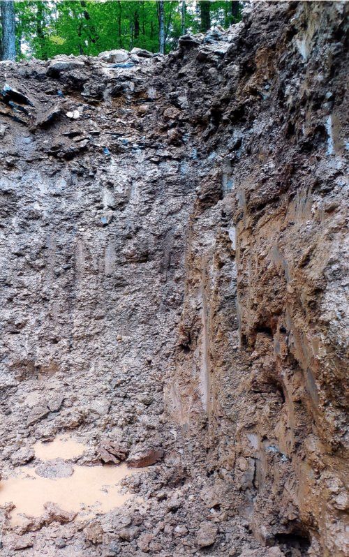 Cutaway view of soil layers in an excavated area, showing varying textures and colors.