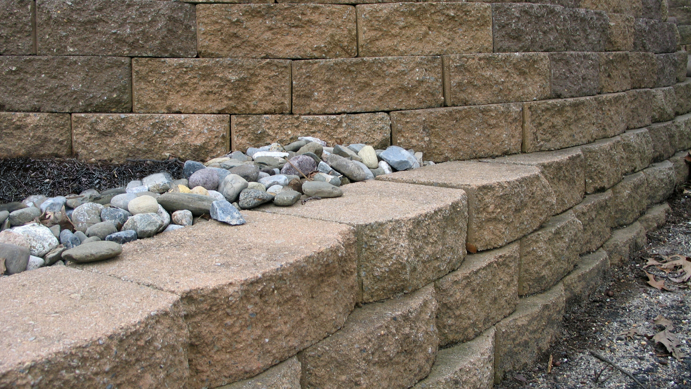 Stone retaining wall with a pile of rocks.