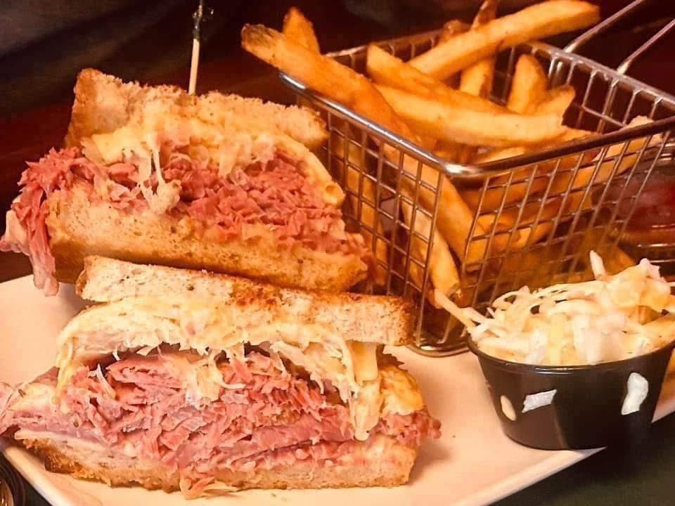 A reuben sandwich with french fries and coleslaw on a plate