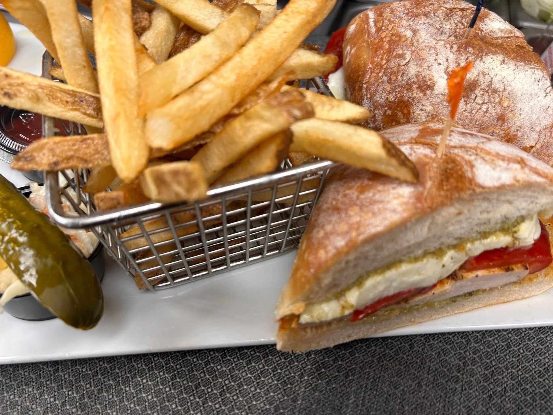 A sandwich with french fries and pickles on a plate