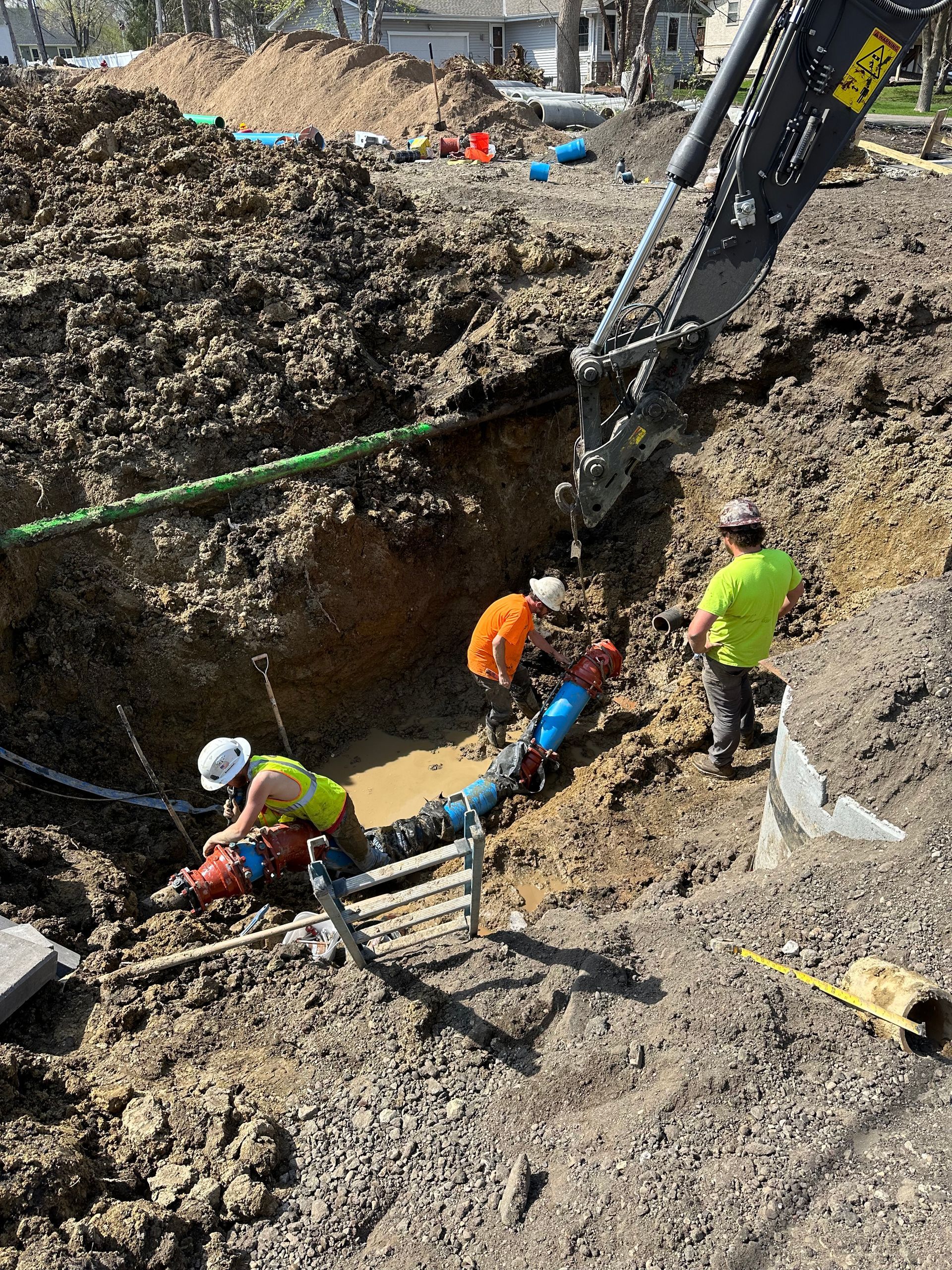 A group of construction workers are working on a pipe in the dirt.