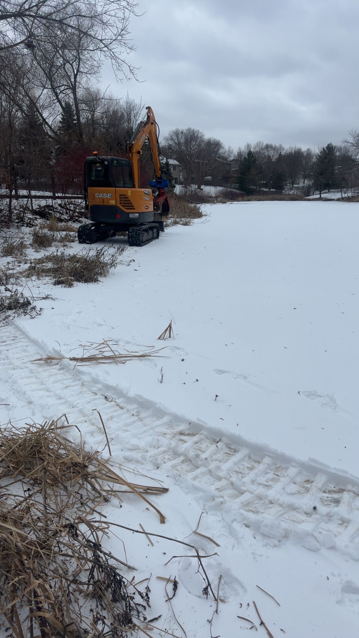 A yellow excavator is standing in the middle of a snow covered field.