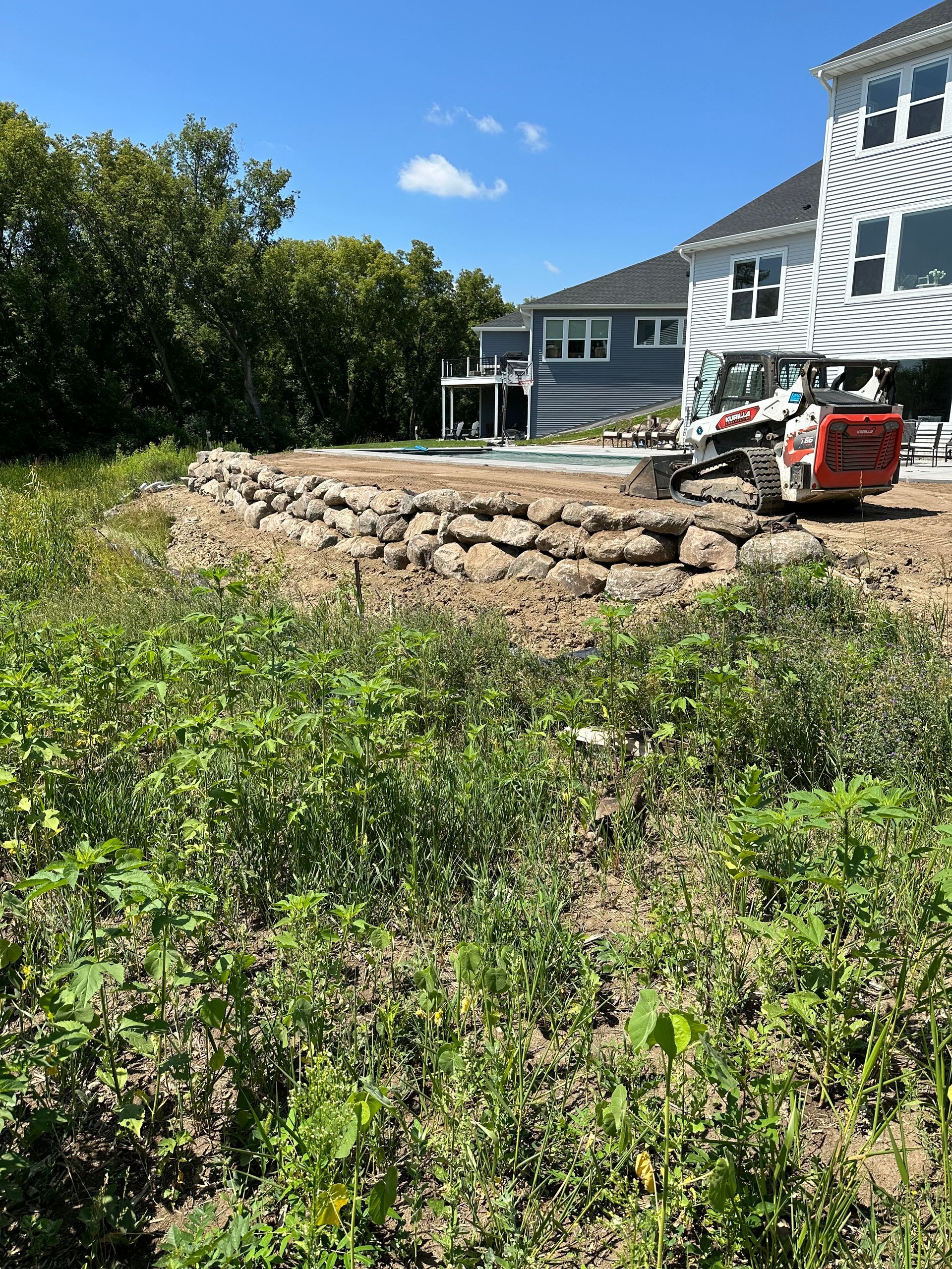 A large house is being built in the background of a lush green field.