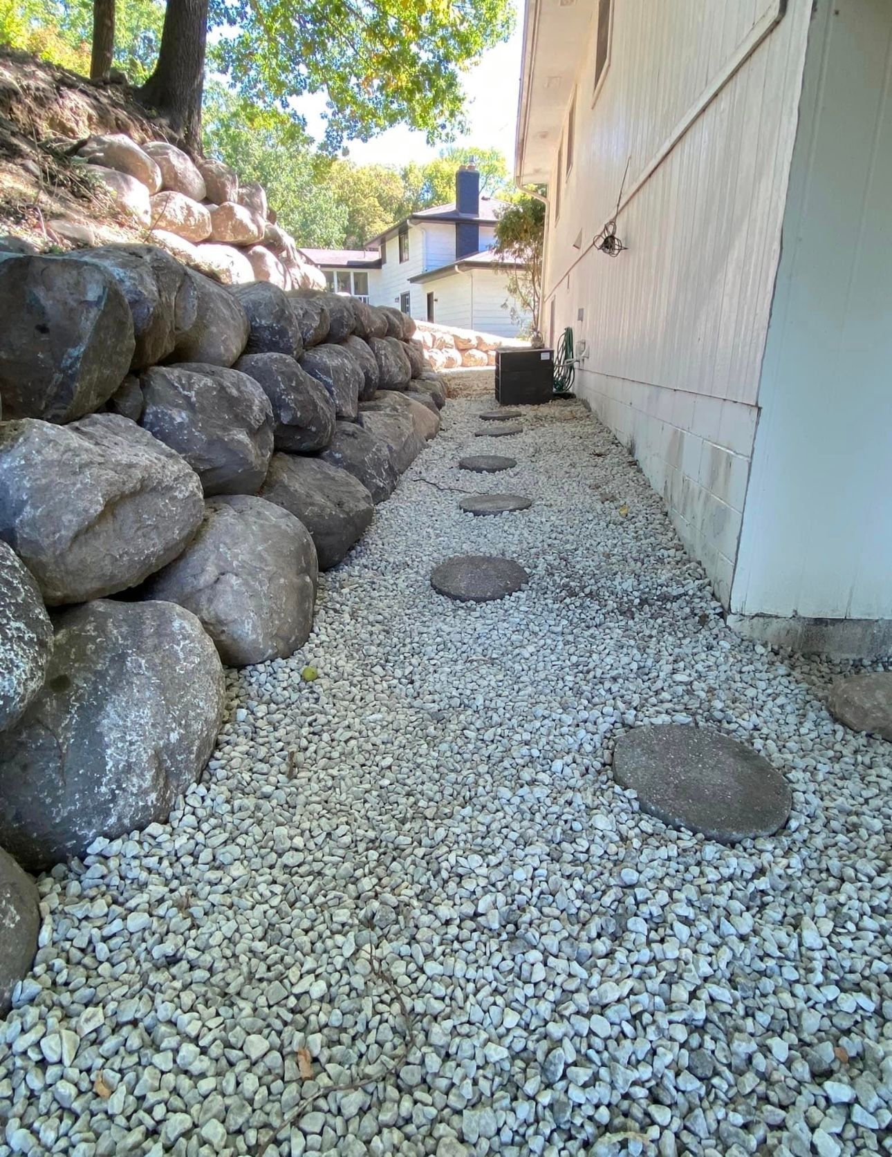 A walkway lined with rocks and gravel next to a house.