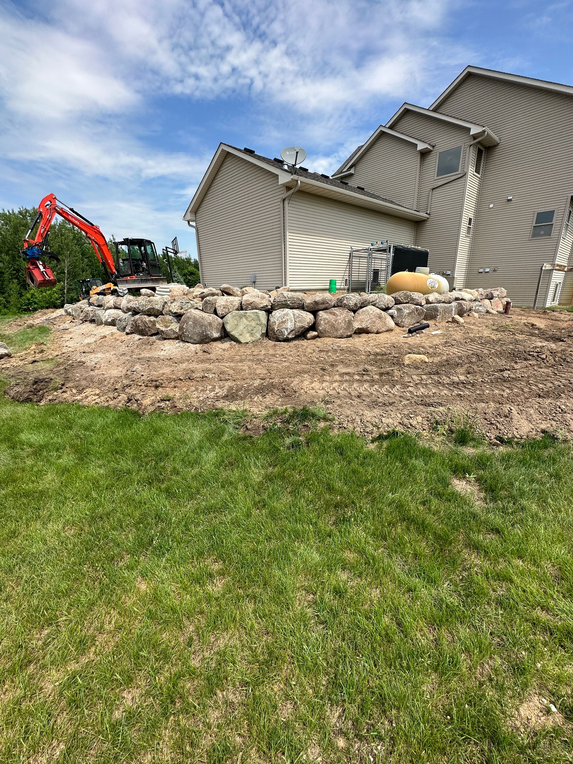 A large rock wall is being built in front of a house.