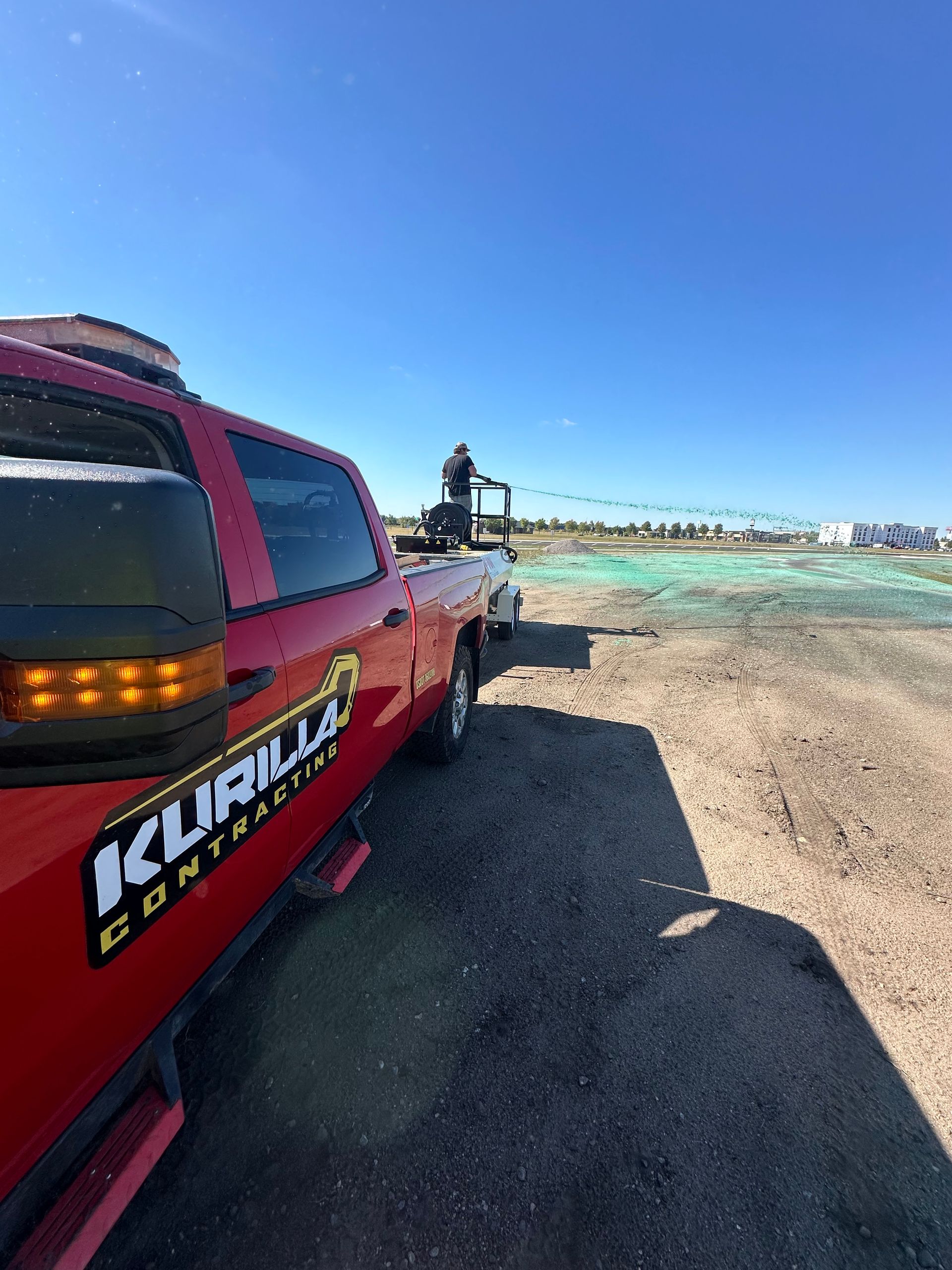 A red truck is parked in the middle of a dirt field.