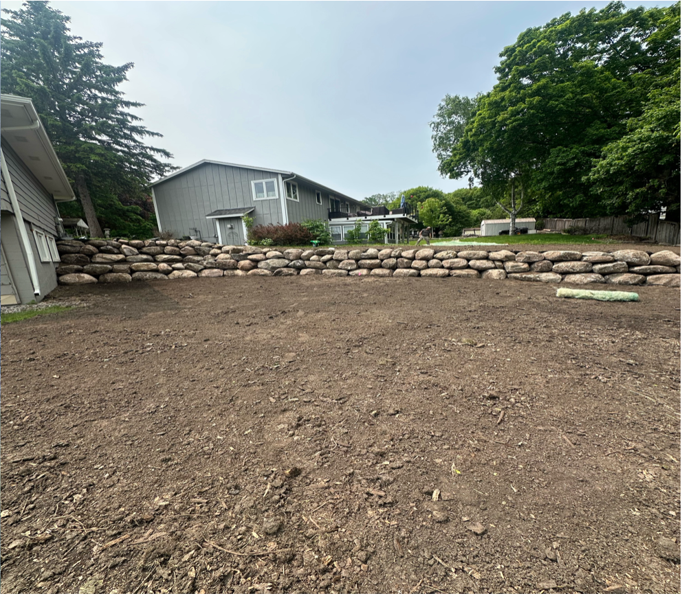 A dirt field with a house in the background