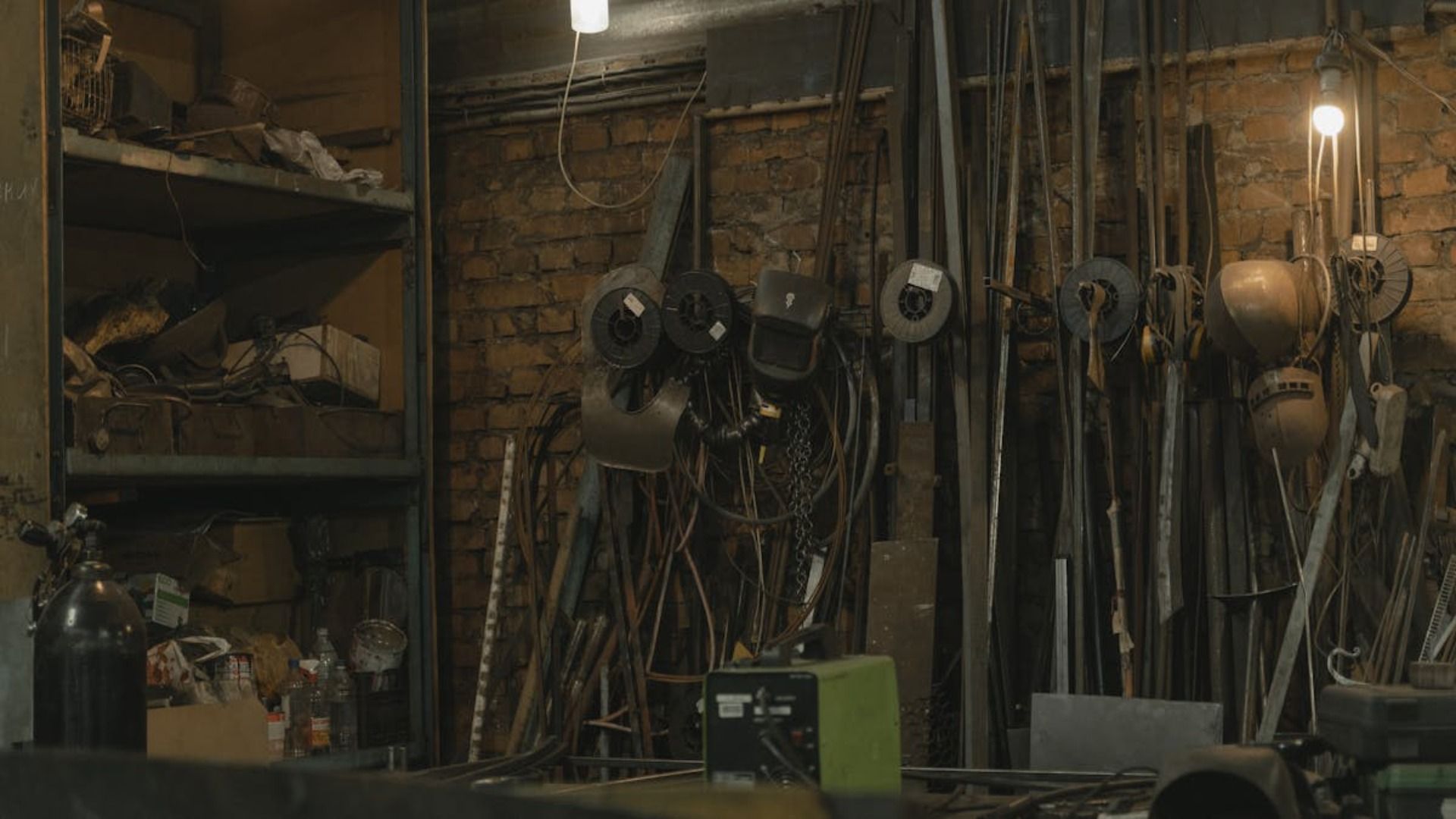 Interior de un taller desordenado con herramientas y piezas de metal colgadas en la pared.