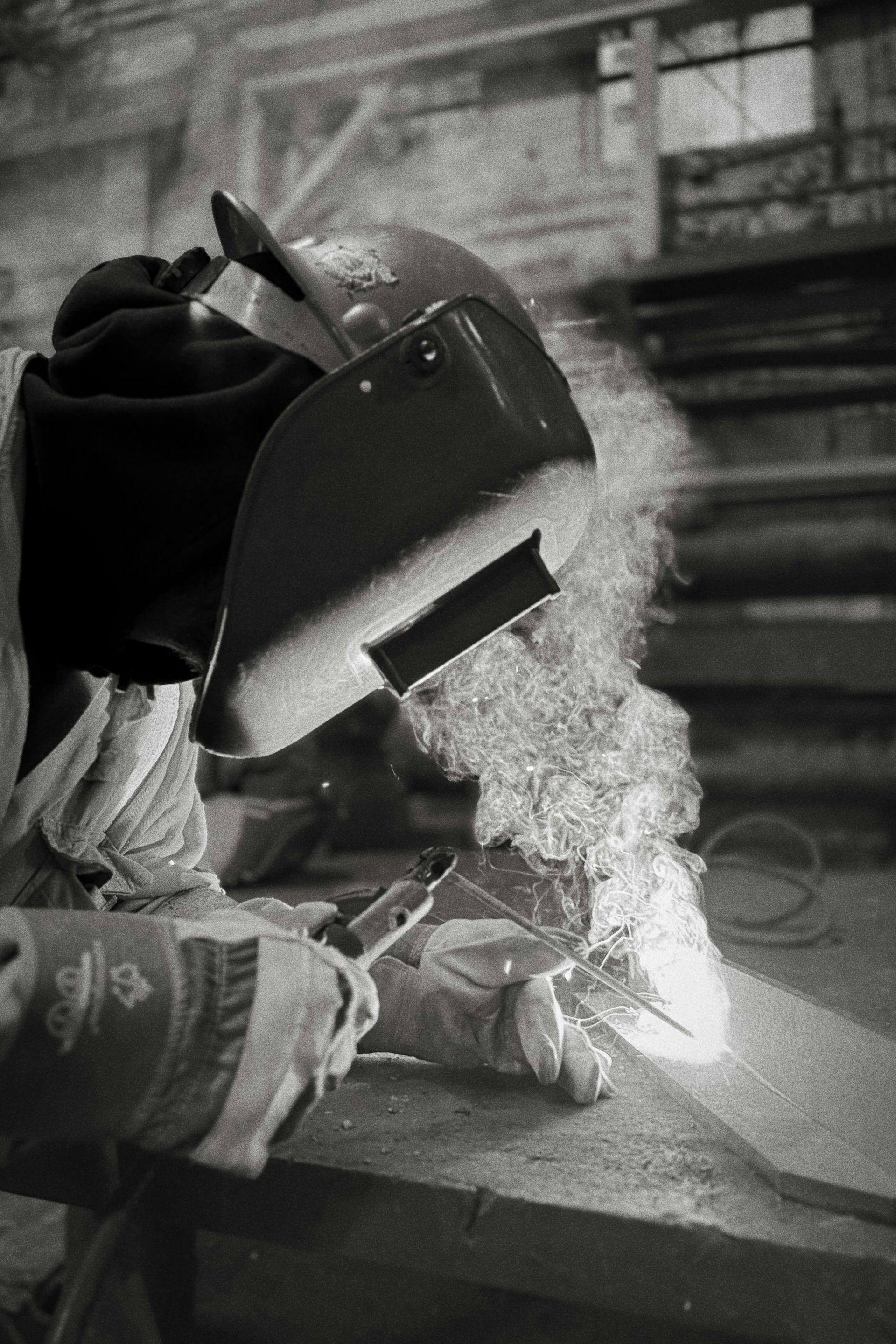 Mano sosteniendo un corazón de metal atravesado por una flecha de metal, contra un cielo nublado y un paisaje urbano.