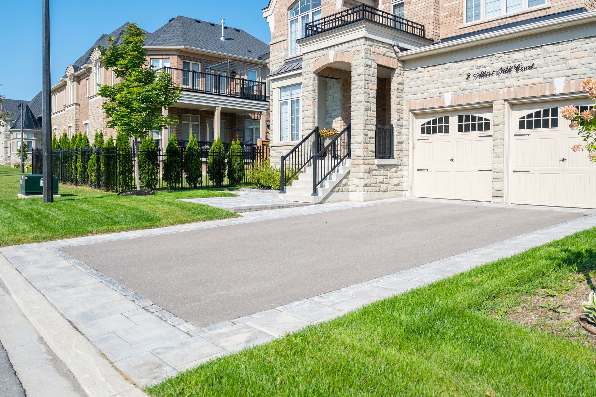 A house with a driveway and garage, bordered by grass and a sidewalk.
