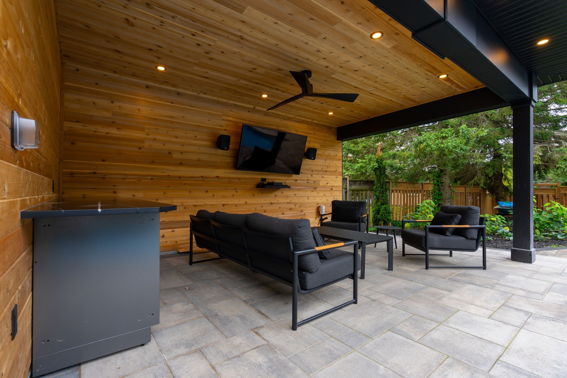 A patio with a couch , chairs , and a ceiling fan.
