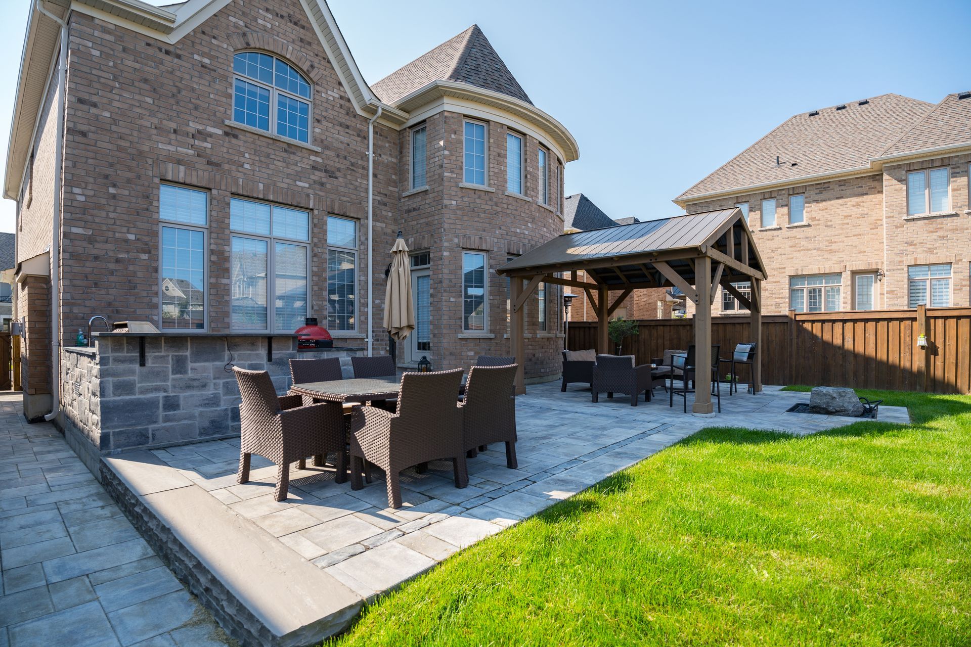 A large brick house with a patio with a table and chairs in front of it.