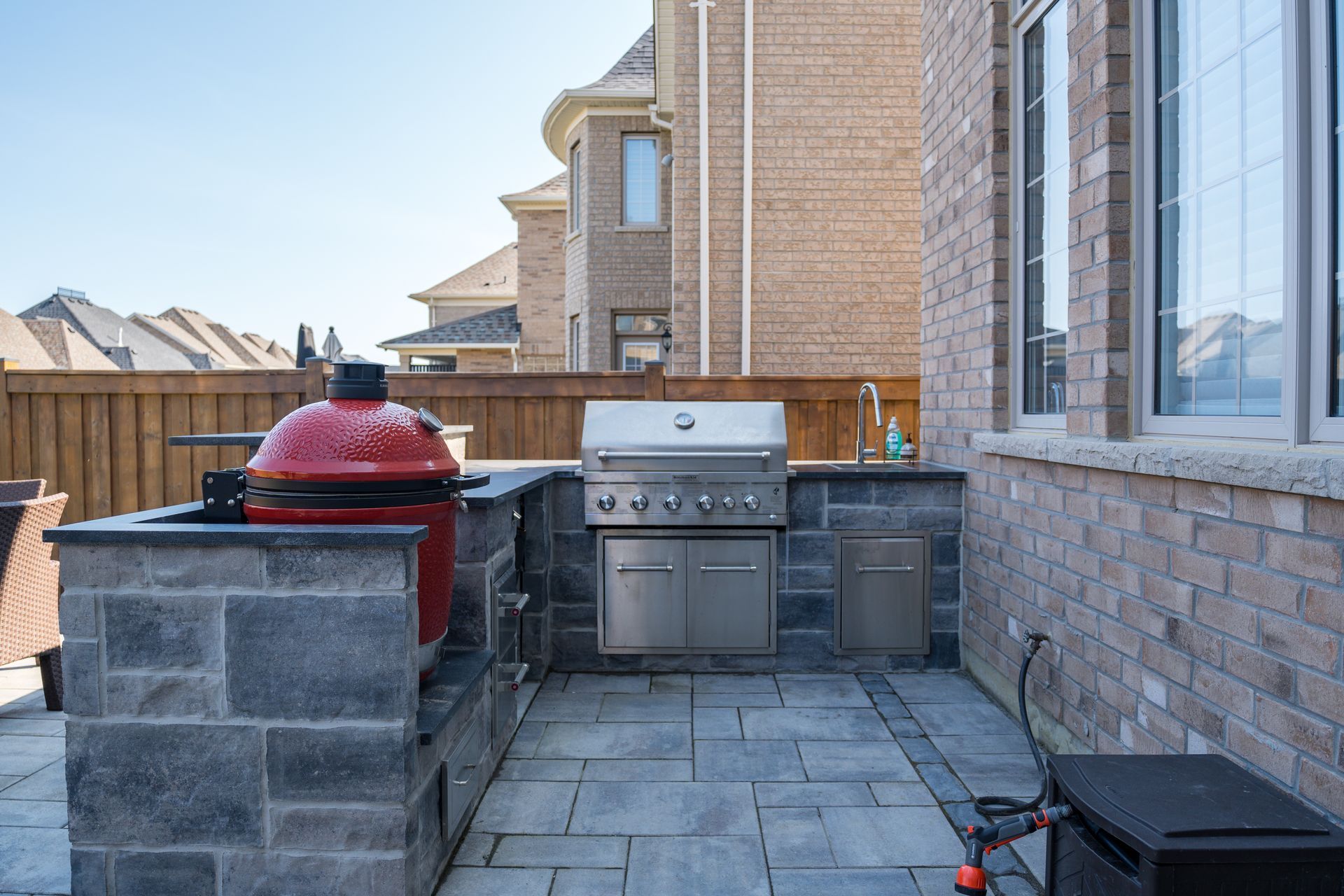 There is a grill in the backyard of a brick house.