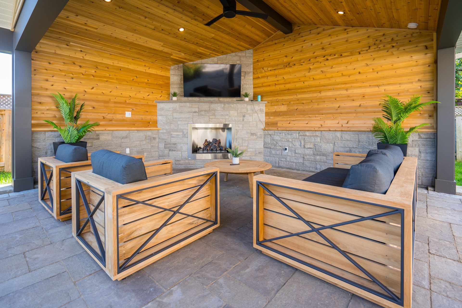 A patio with wooden furniture and a fireplace.
