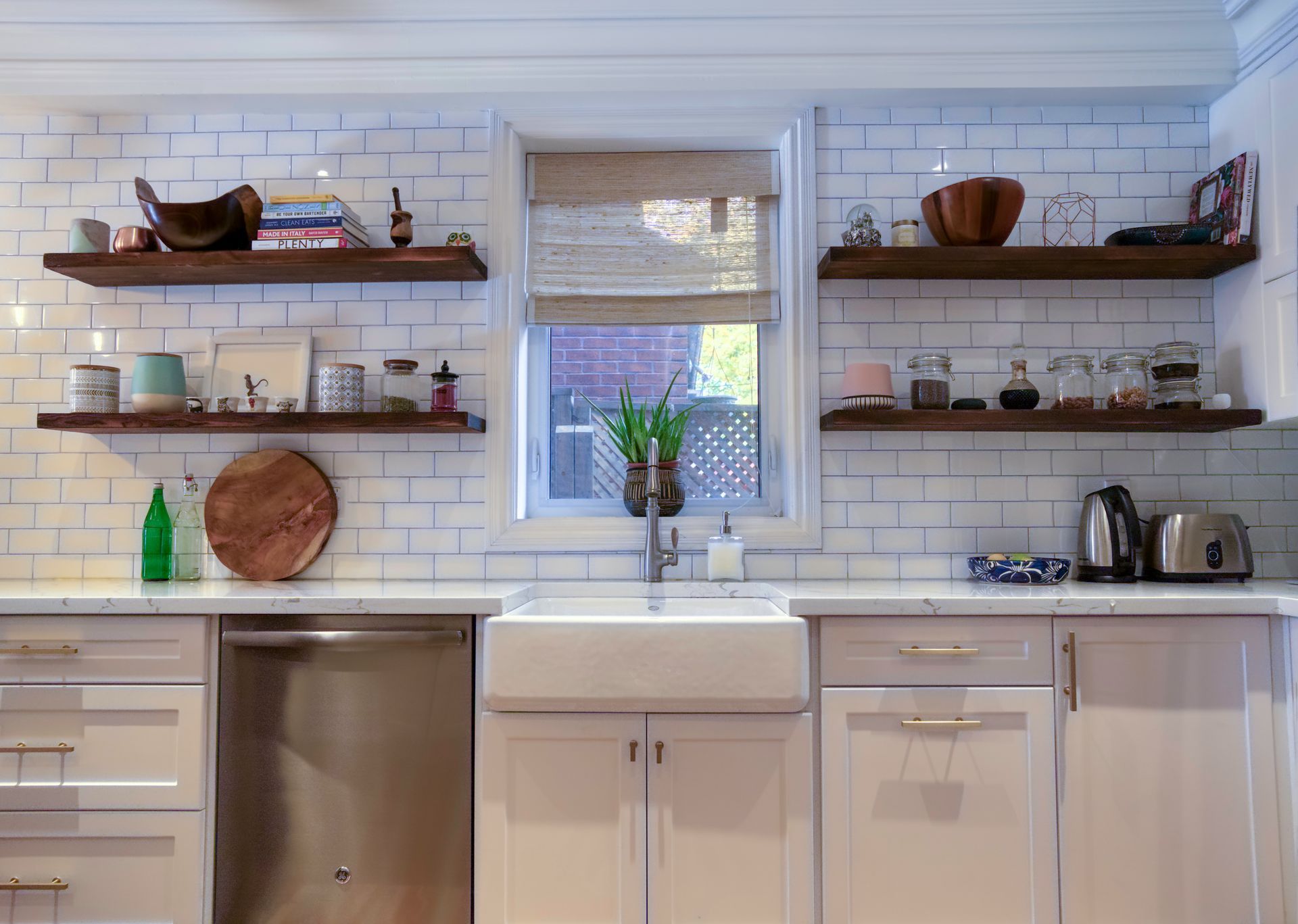 White kitchen with floating shelves, white subway tile backsplash, and a farmhouse sink.