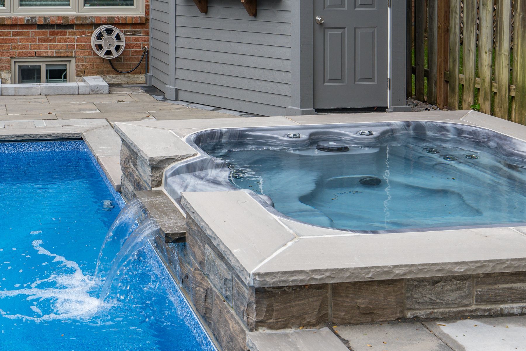 A hot tub is sitting next to a swimming pool.