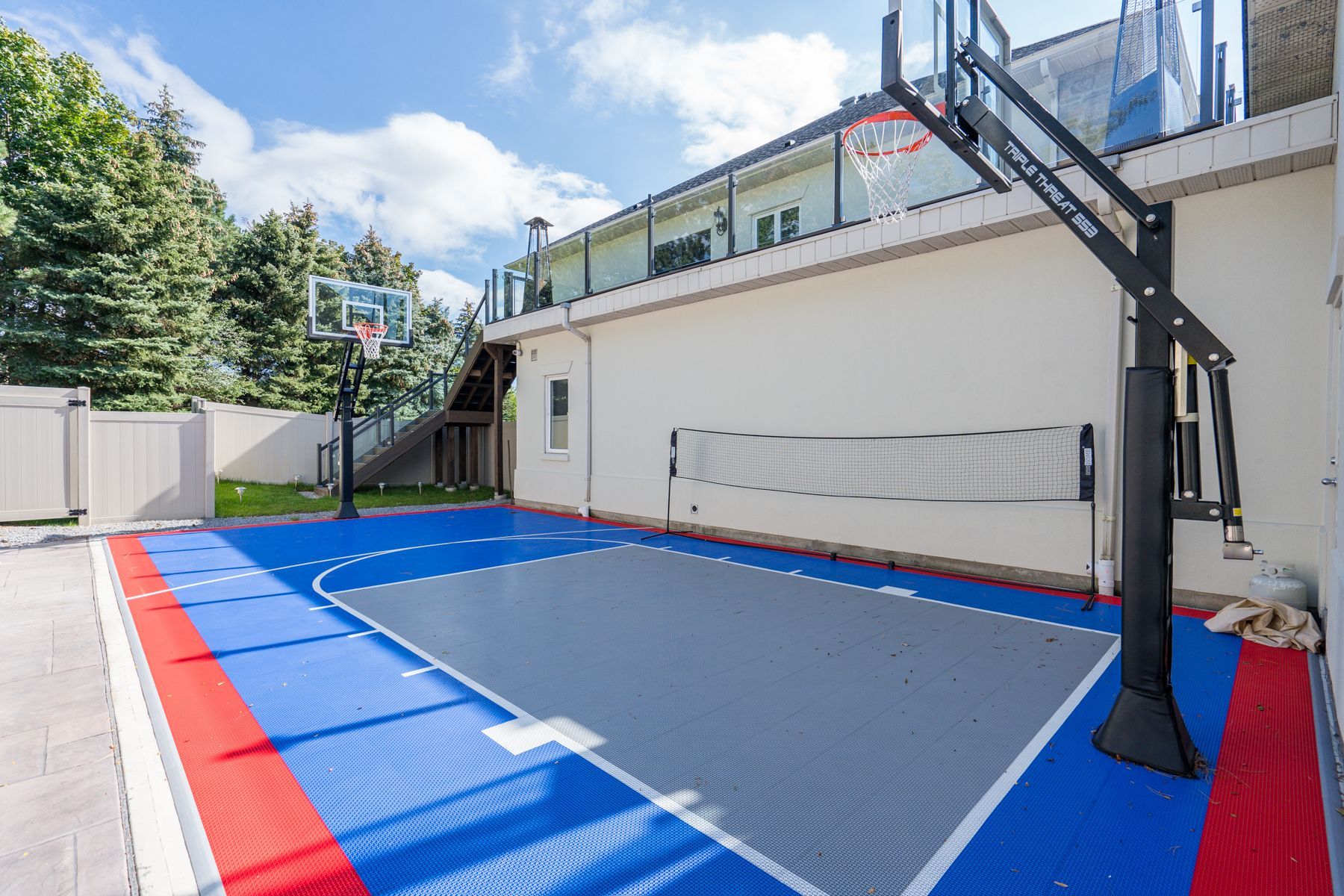 There is a basketball court in the backyard of a house.