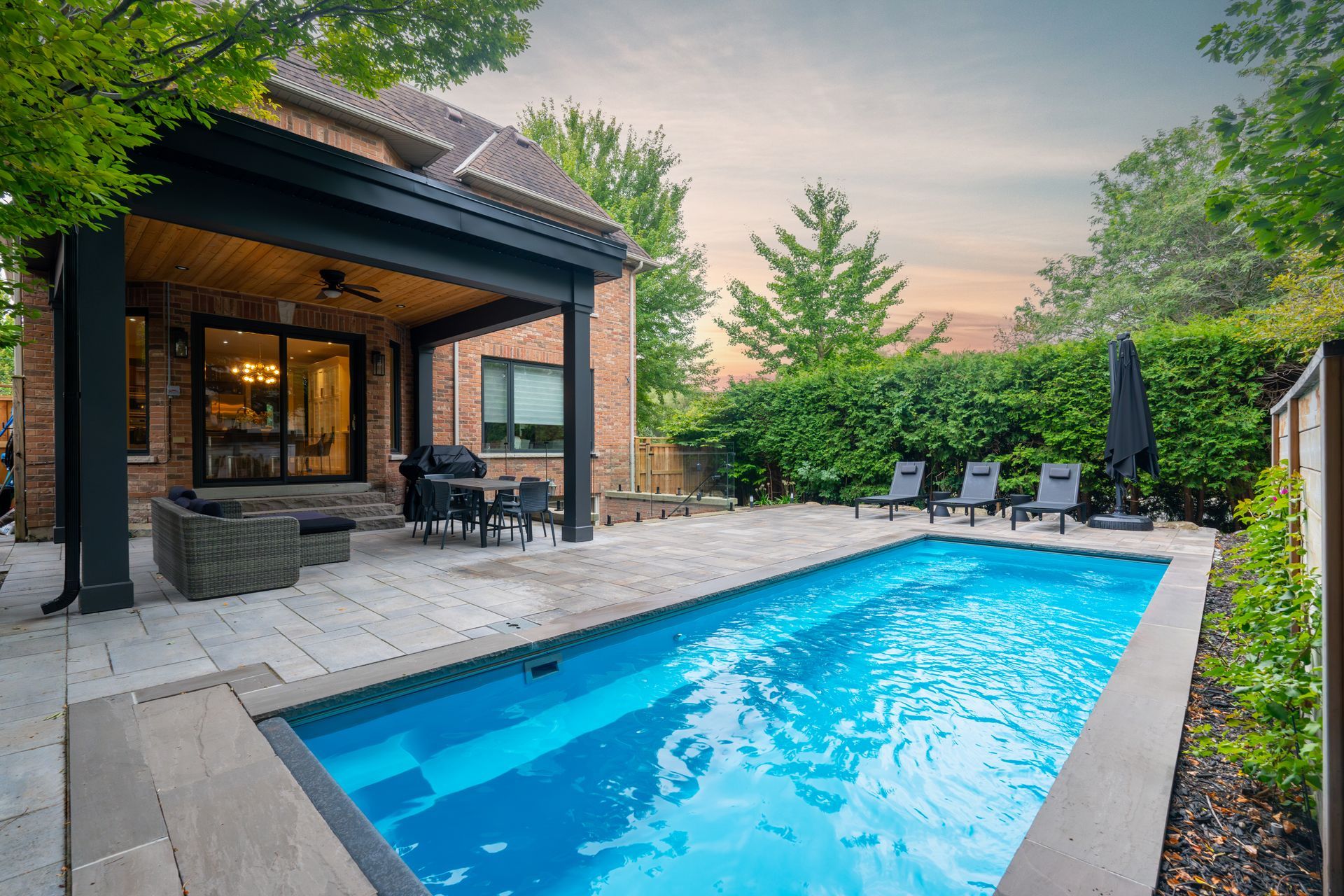 There is a large swimming pool in the backyard of a house.