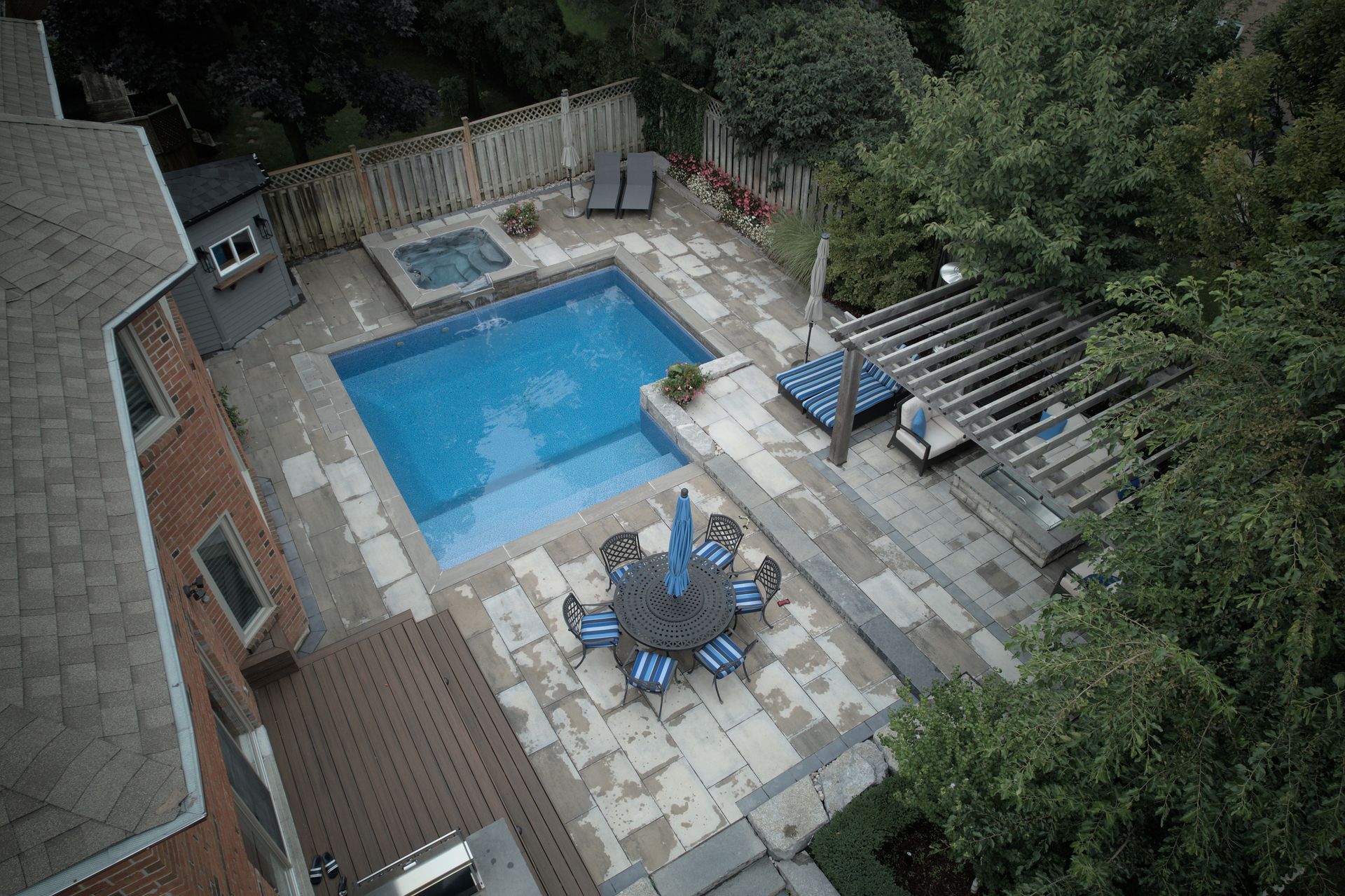 An aerial view of a backyard with a large swimming pool and a table and chairs.
