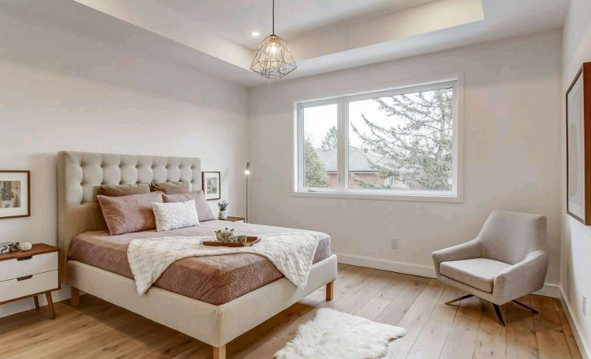 A bedroom with a bed, chair, nightstand and window.