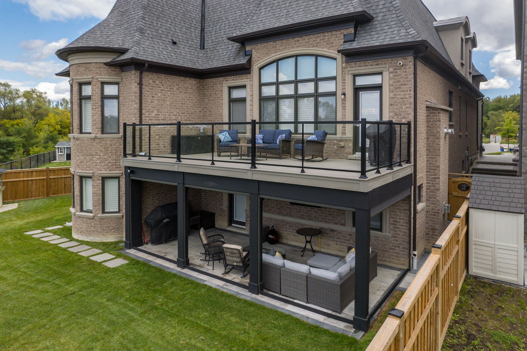 The back of a large brick house with a large balcony.