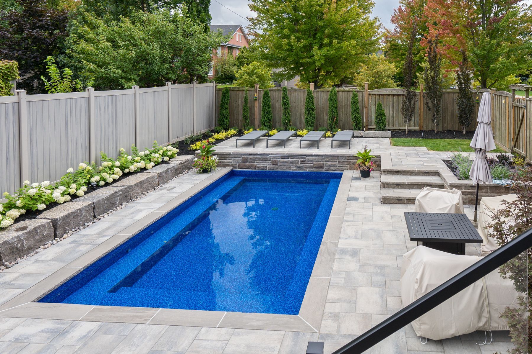 A large swimming pool is in the backyard of a house.