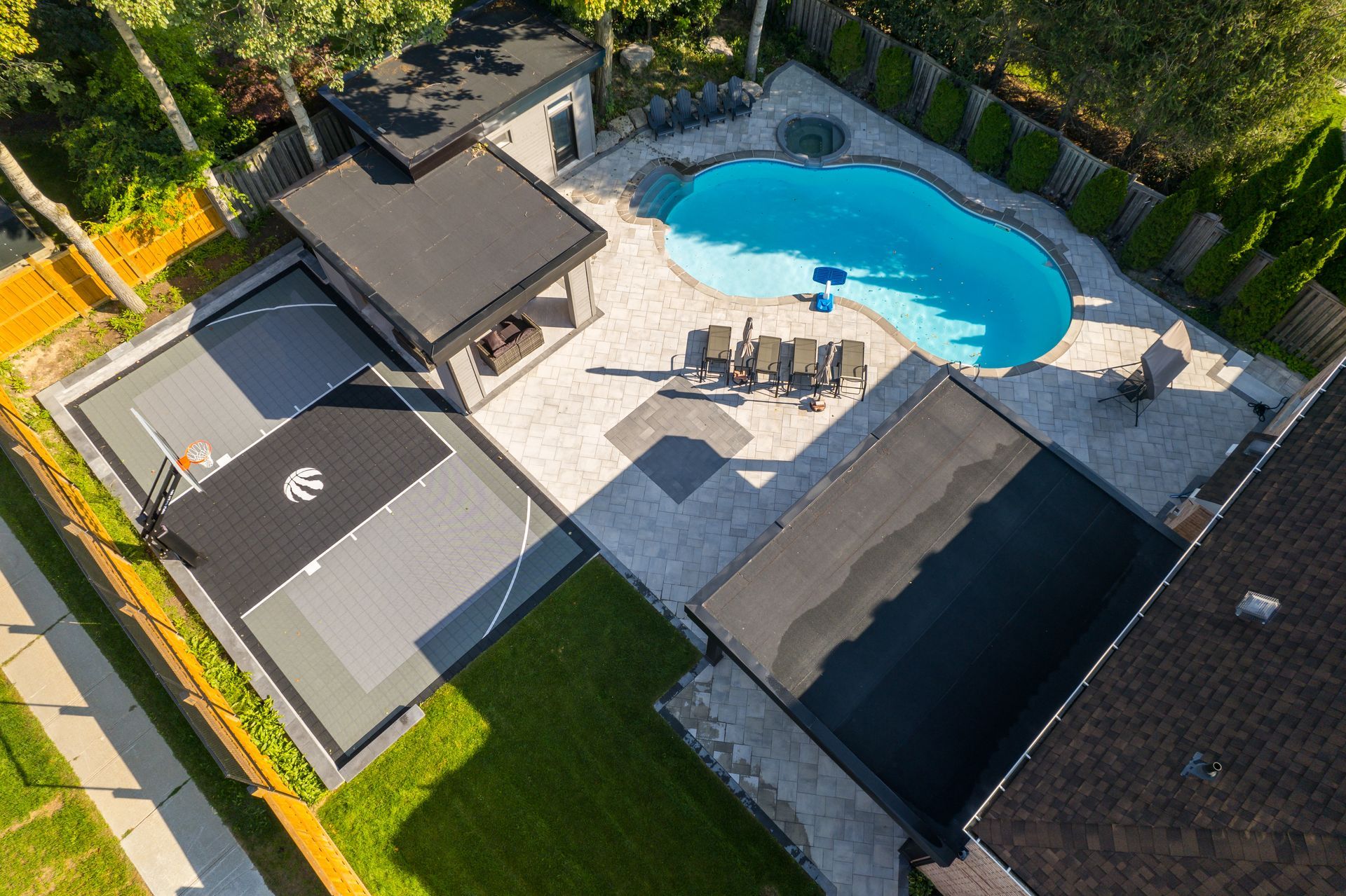 An aerial view of a backyard with a basketball court and a pool.