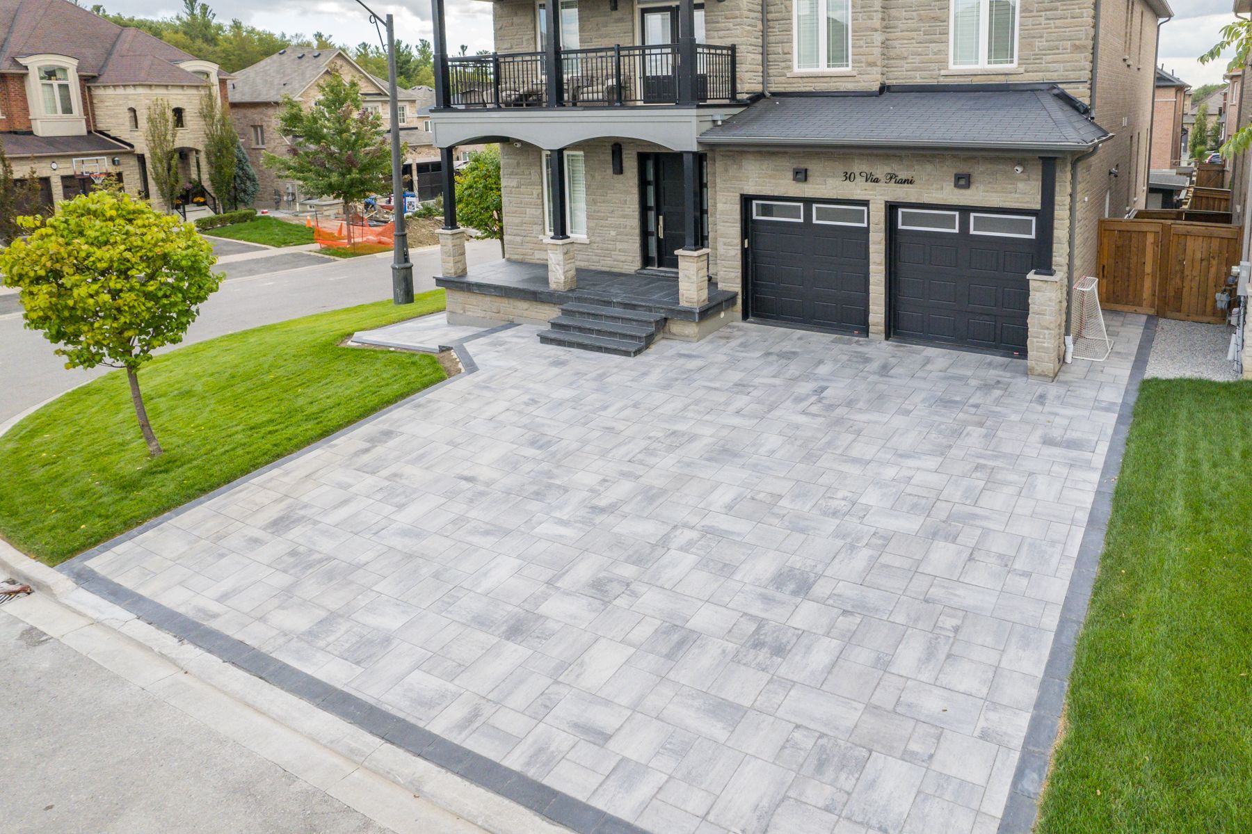 An aerial view of a house with a large driveway in front of it.
