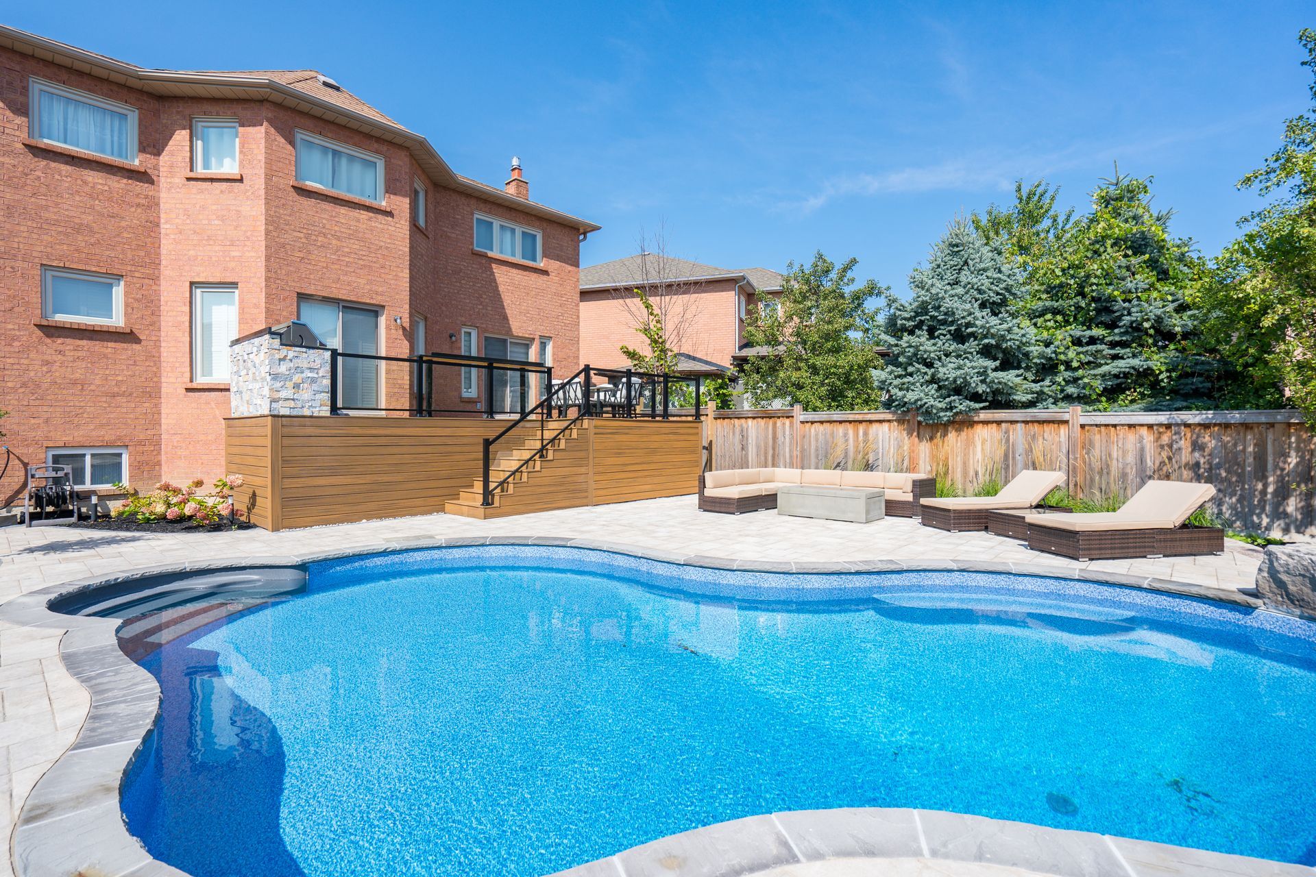 A large swimming pool is in the backyard of a house.