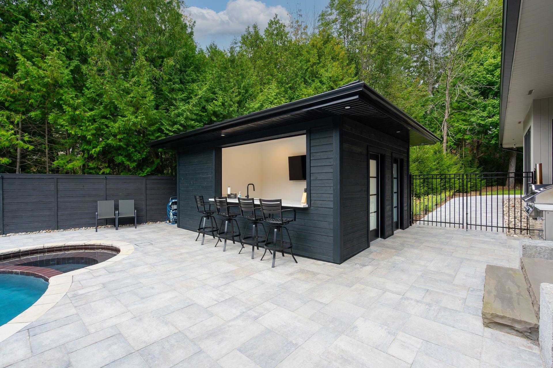 A black building with a kitchen and a pool in the backyard.