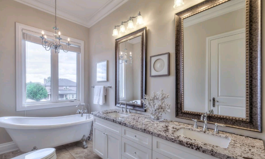 A bathroom with a tub, sink, mirrors and two windows.