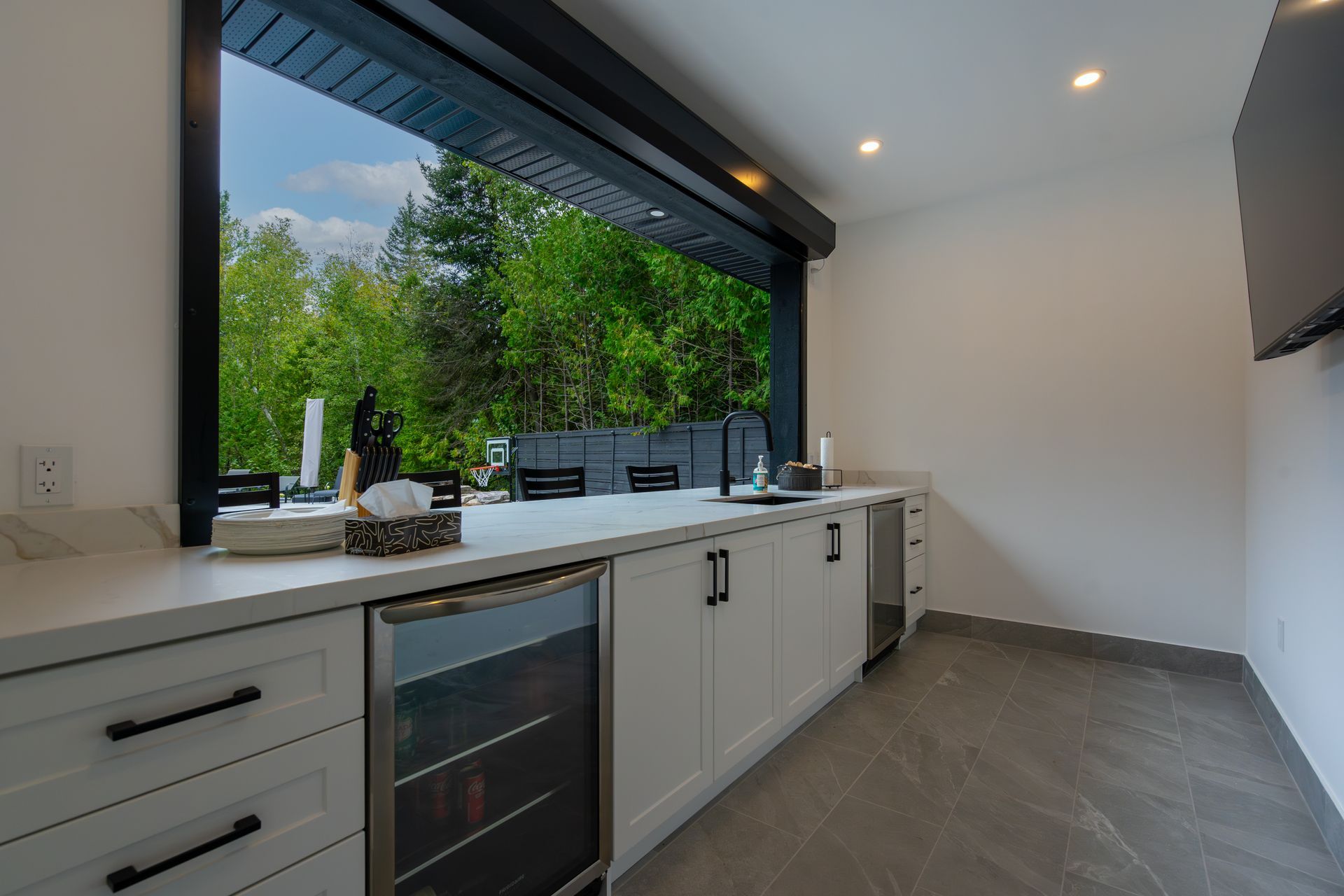 There is a large window in the kitchen with a view of the trees.