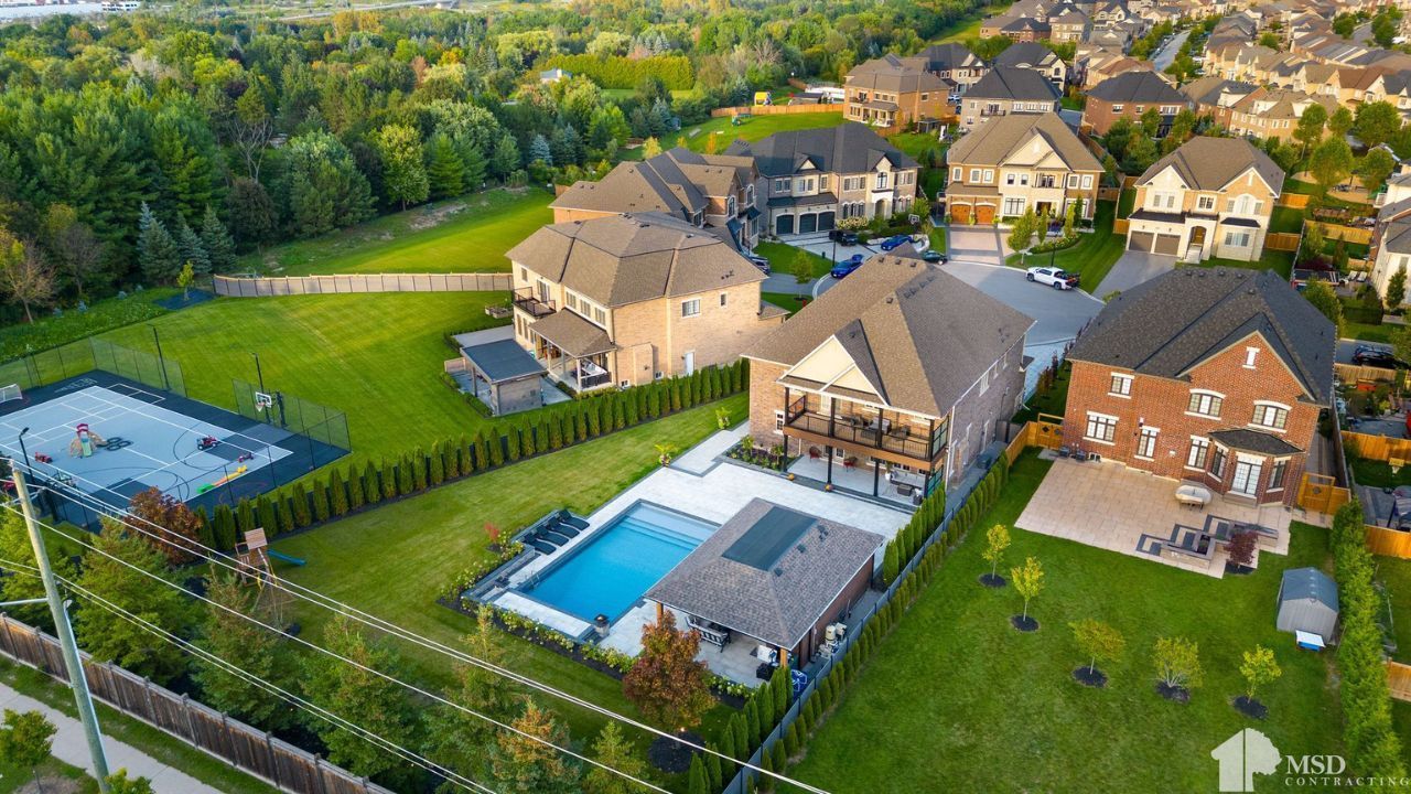 Aerial view of upscale suburban homes with pools, green lawns, and a playground by MSD Contracting